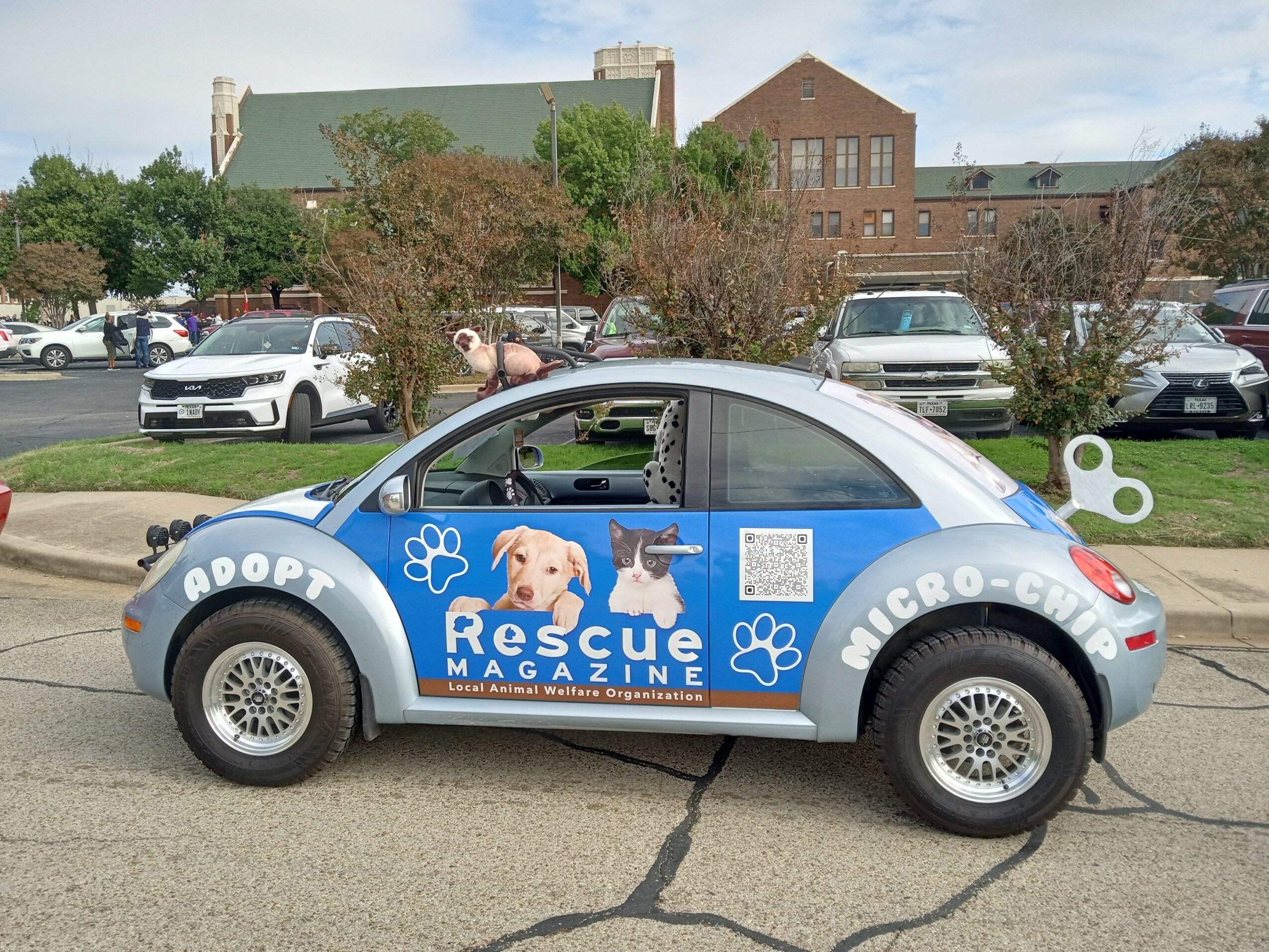 Dog rescue vehicle with blue and white design, paw prints, and rescue magazine logo parked on street.