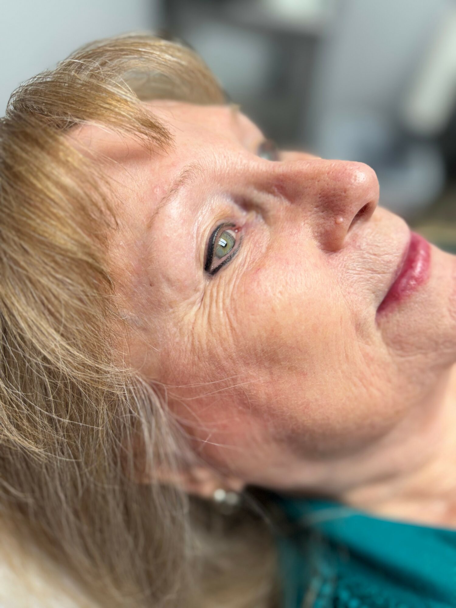 Close-up of a woman lying down, looking upward with light-colored hair and visible facial features.