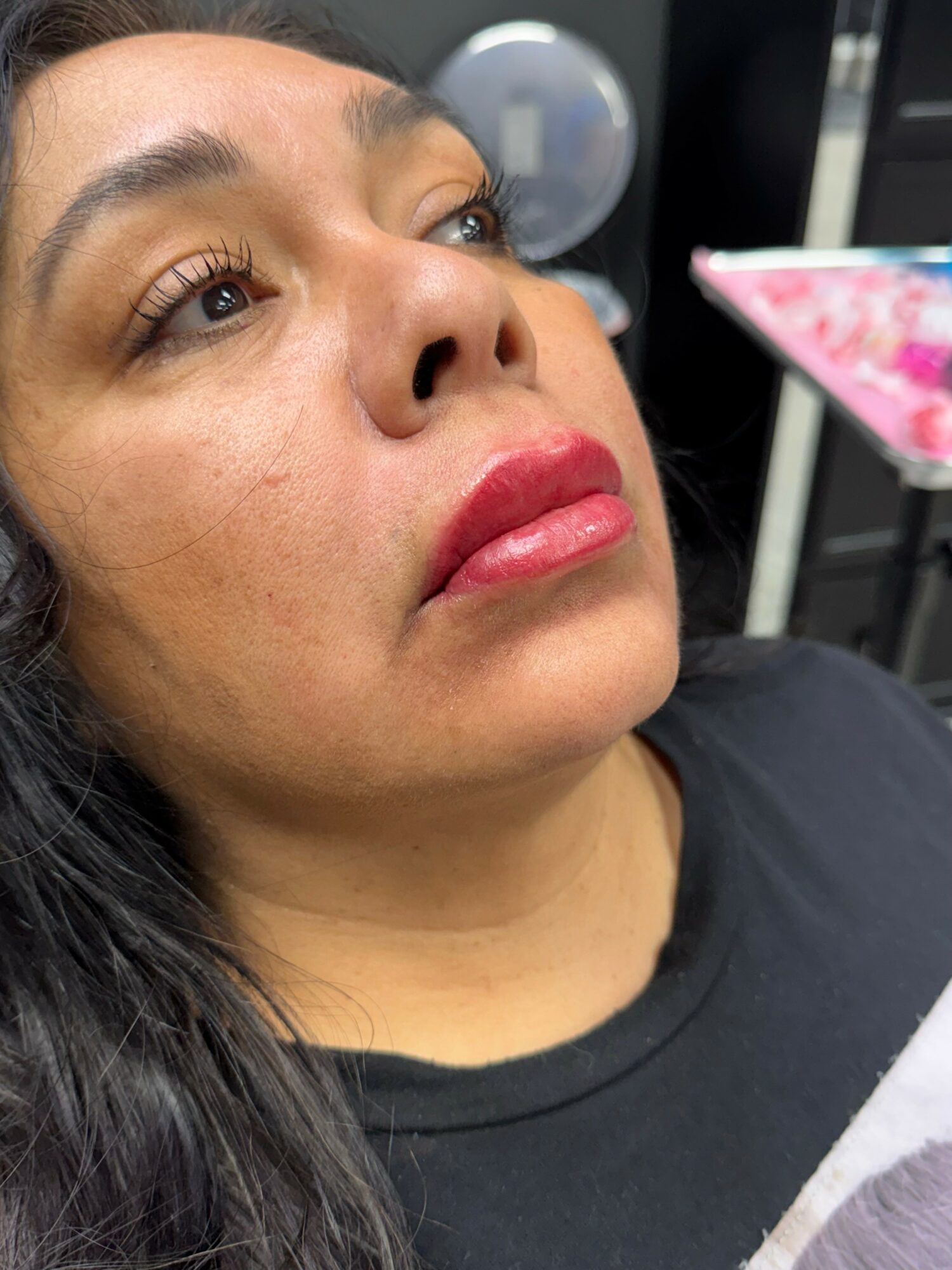 Close-up of a woman's face with makeup, looking upward, with a blurred background.