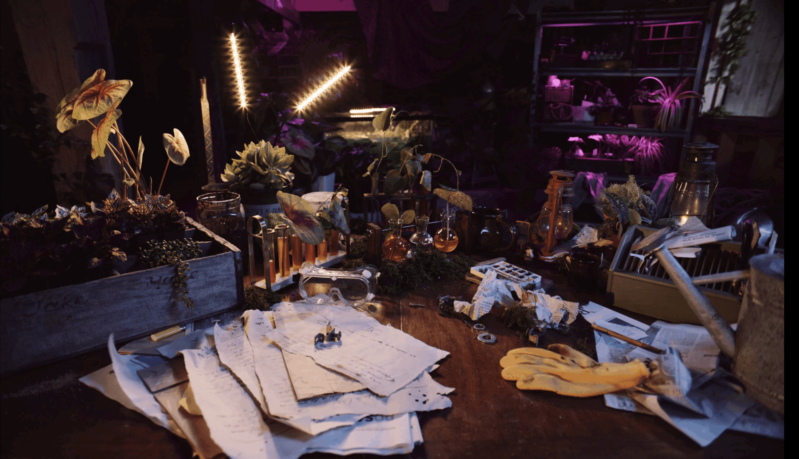 Cluttered table with papers, gloves, and various objects in a dimly lit room.