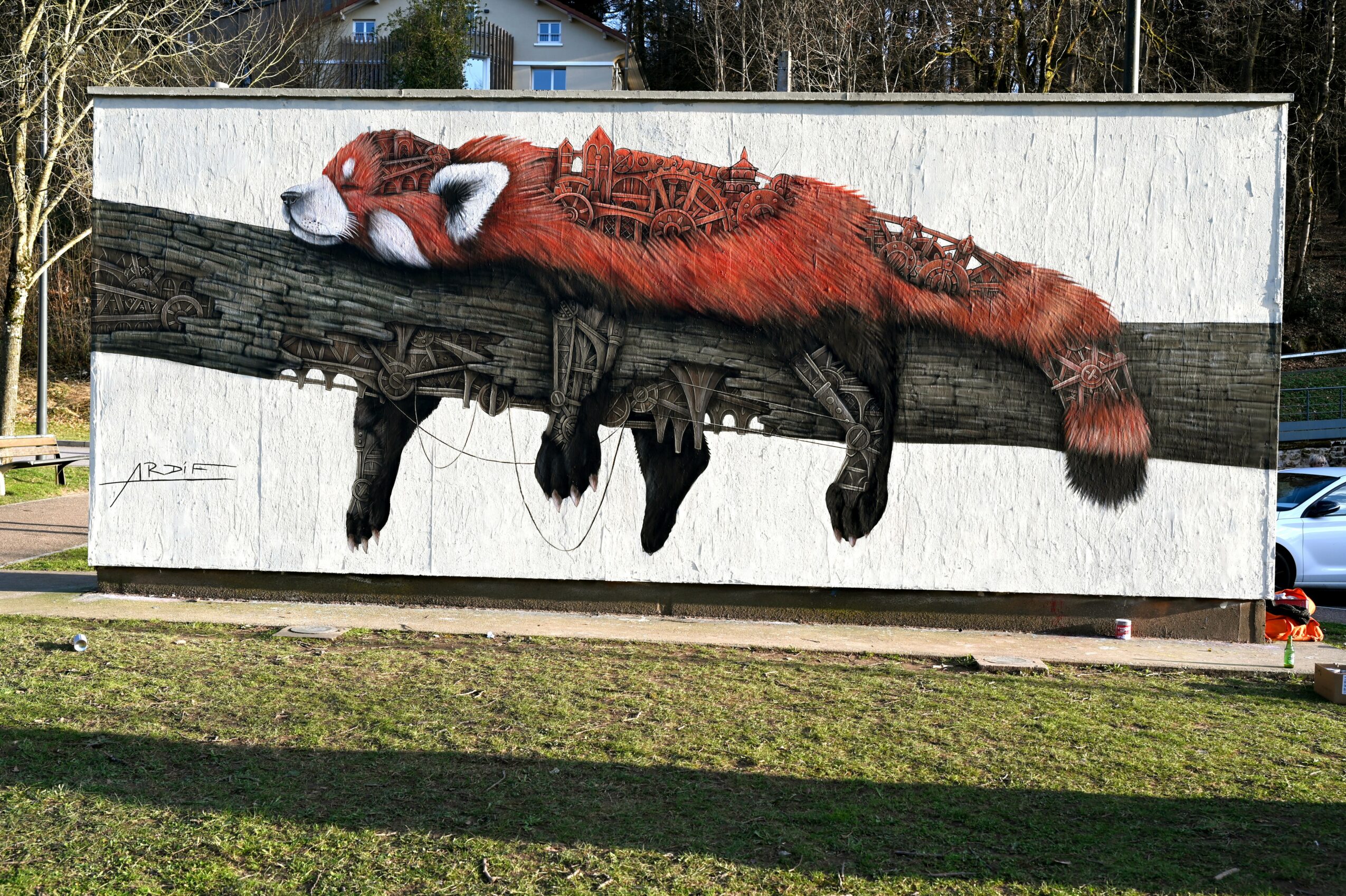 A mural of a red fox wearing glasses, lying on a wooden log, painted on a large white wall.