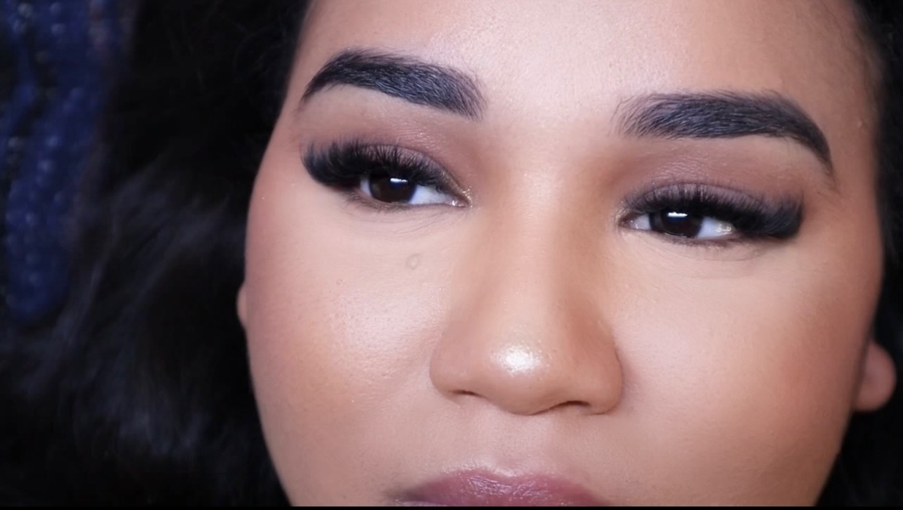 Close-up of a woman's face focusing on her eyes and eyebrows, with makeup and dark hair visible.