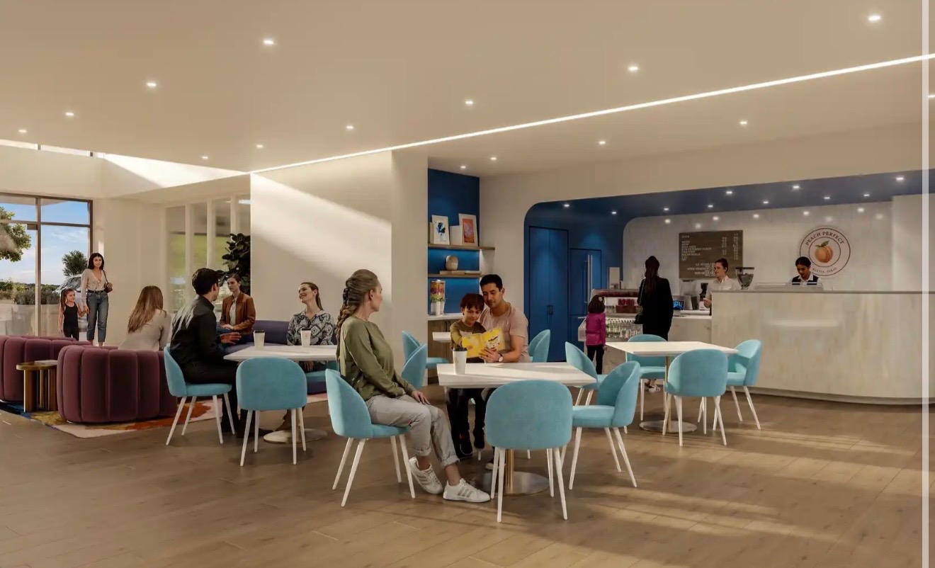 People sitting at tables in a modern, well-lit cafe with a curved counter and blue accents.