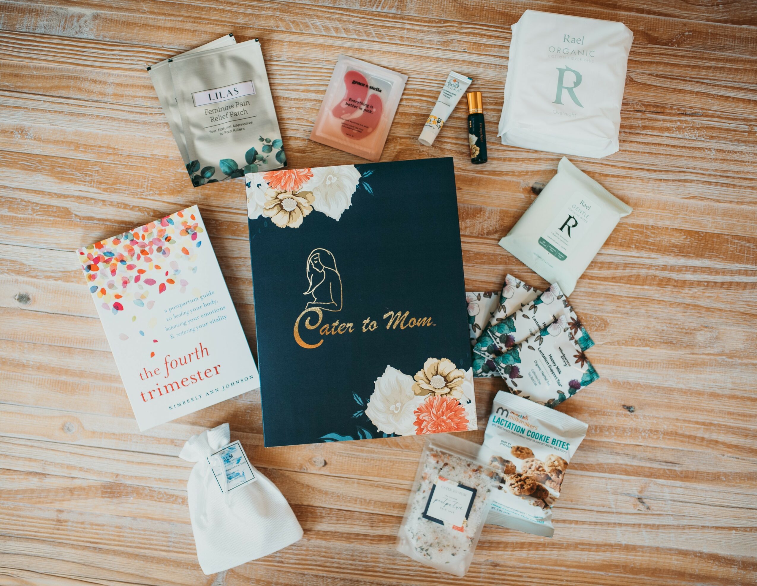 Baby shower gift set with a book, diapers, wipes, and small items on a wooden surface.