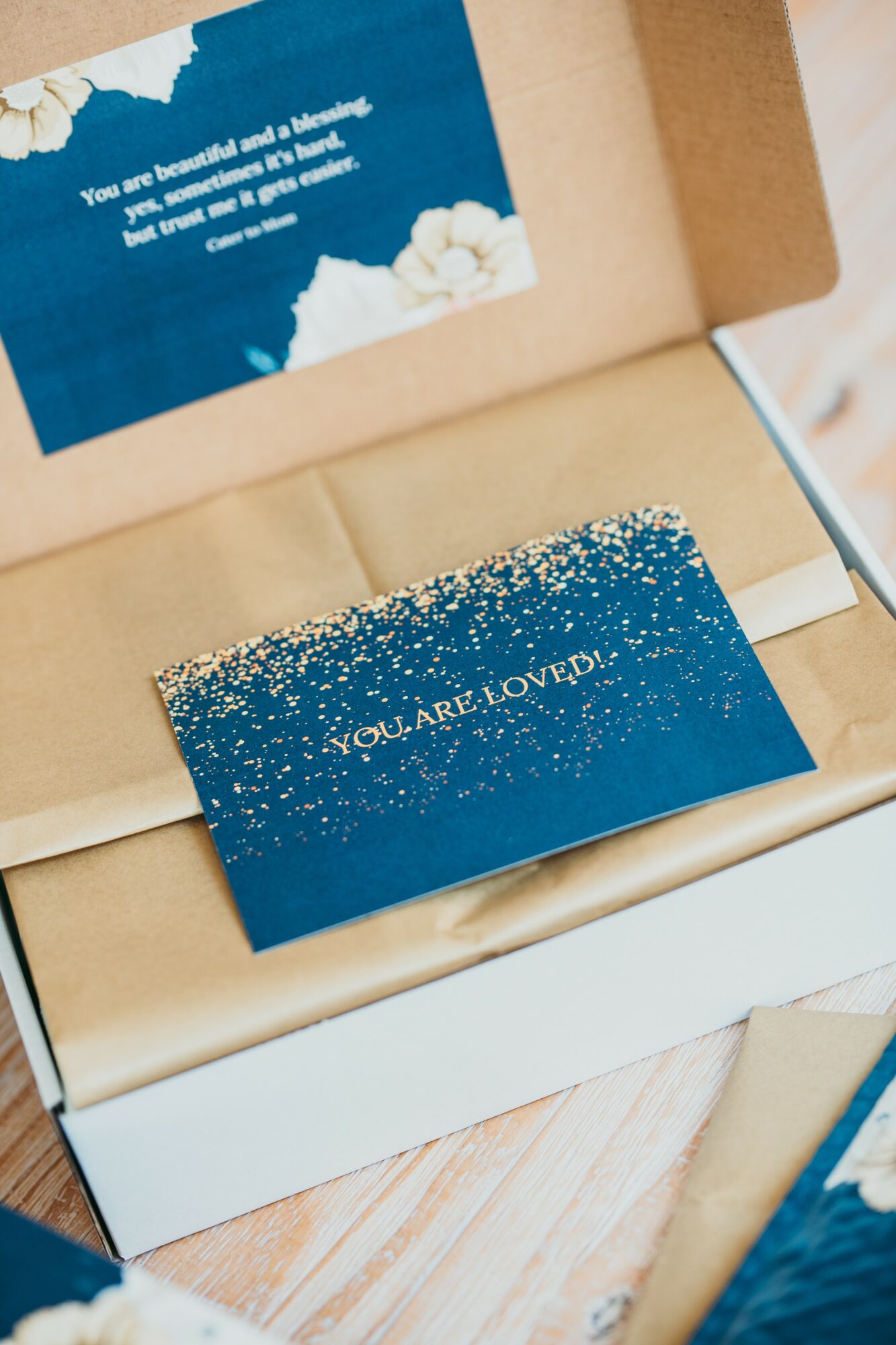 Open box with a blue card reading 'You are loved so much!' and a glittery blue card with 'You are loved!' inside.