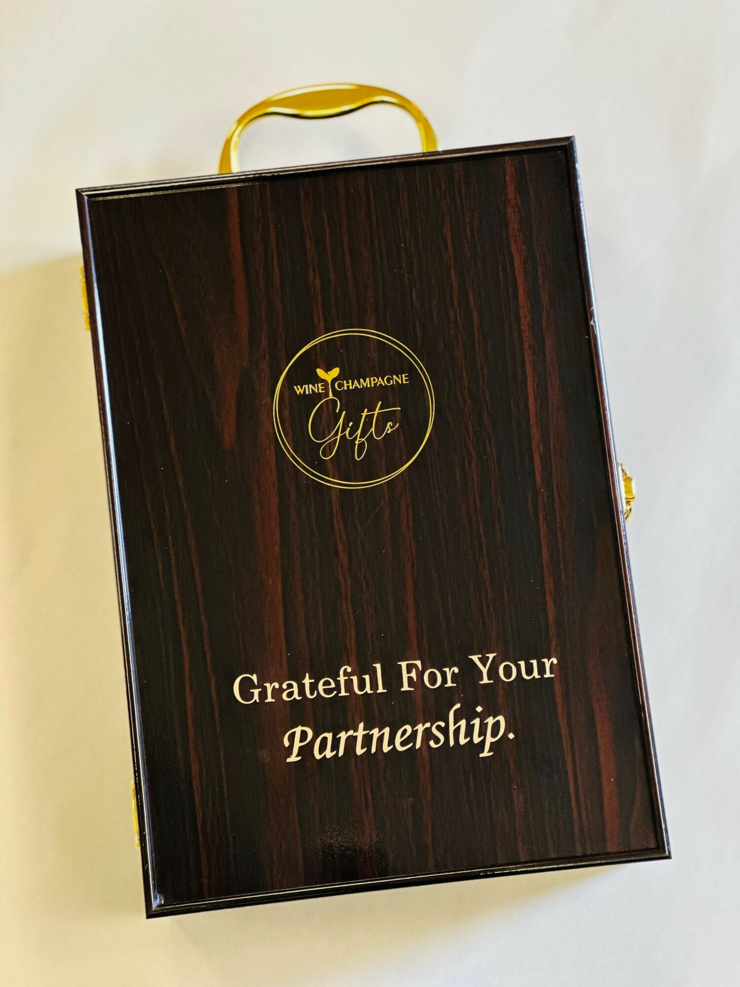 A black gift box with a yellow handle, featuring a gold logo and the text 'Grateful For Your Partnership.'