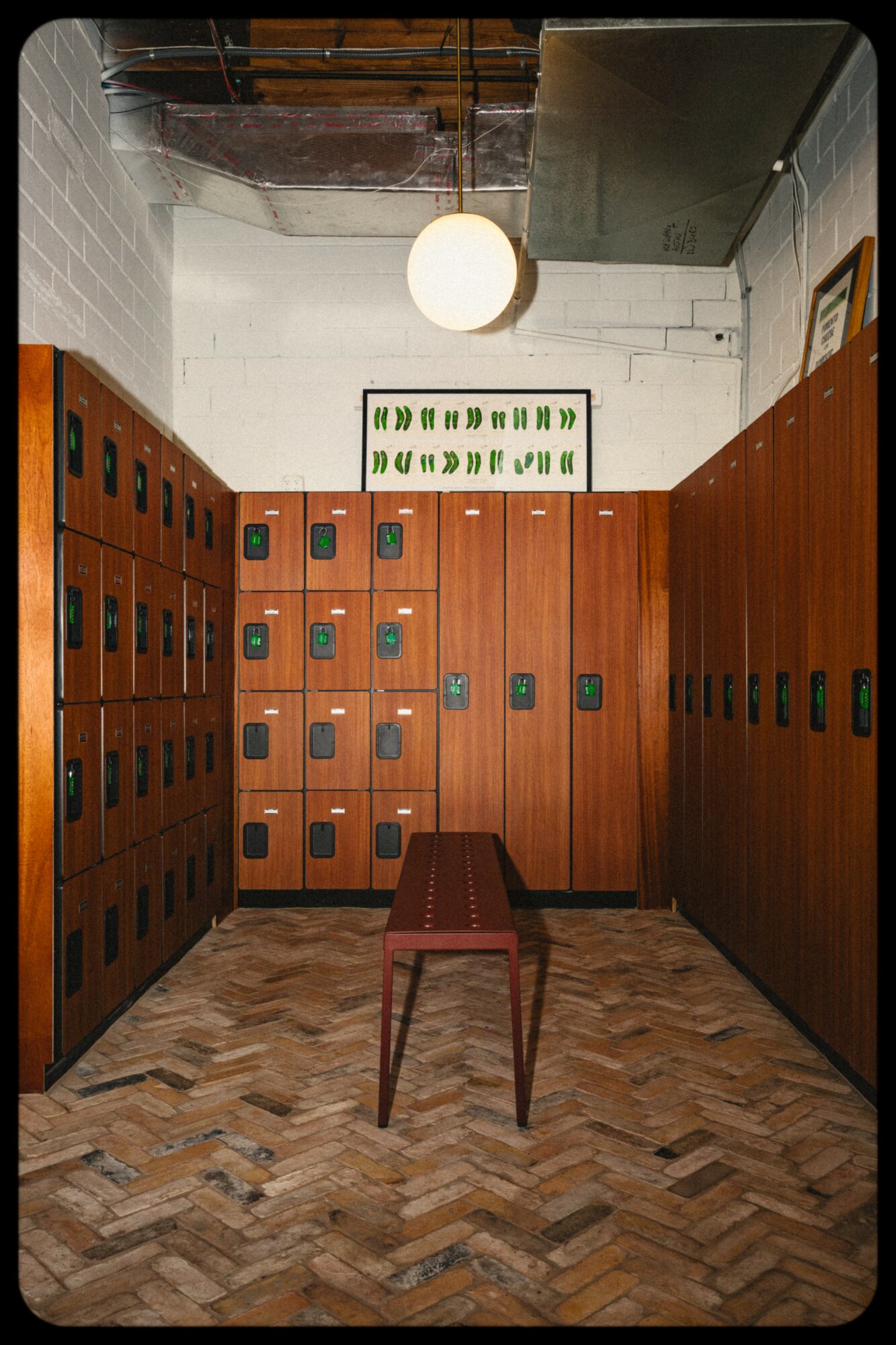 Locker room with wooden lockers, a small stool, and a hanging light fixture.