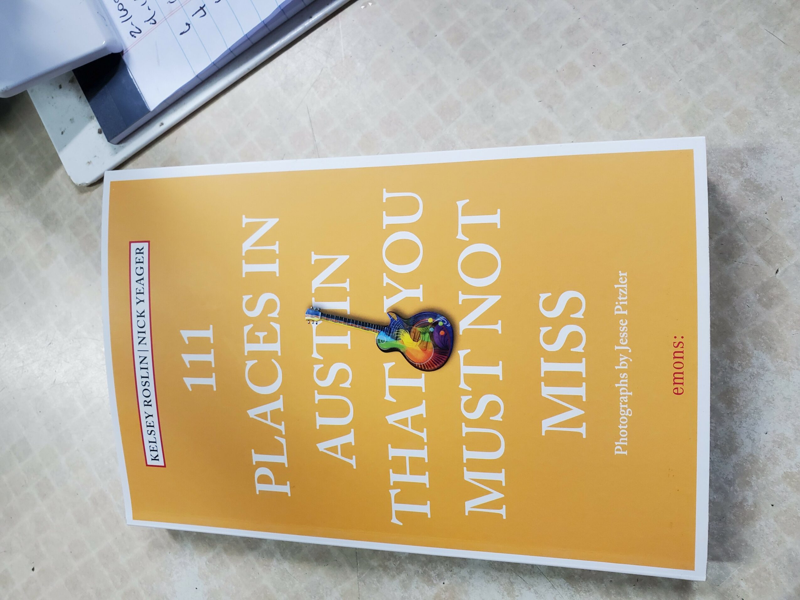 A yellow poster with white text reading, '111 PLACES IN AUSTRALIA THAT YOU MUST NOT MISS,' and a small colorful logo at the bottom right.