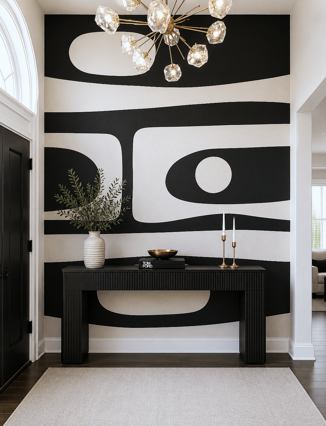 Black and white abstract wall art with a black console table, a white vase with greenery, and two candlesticks.