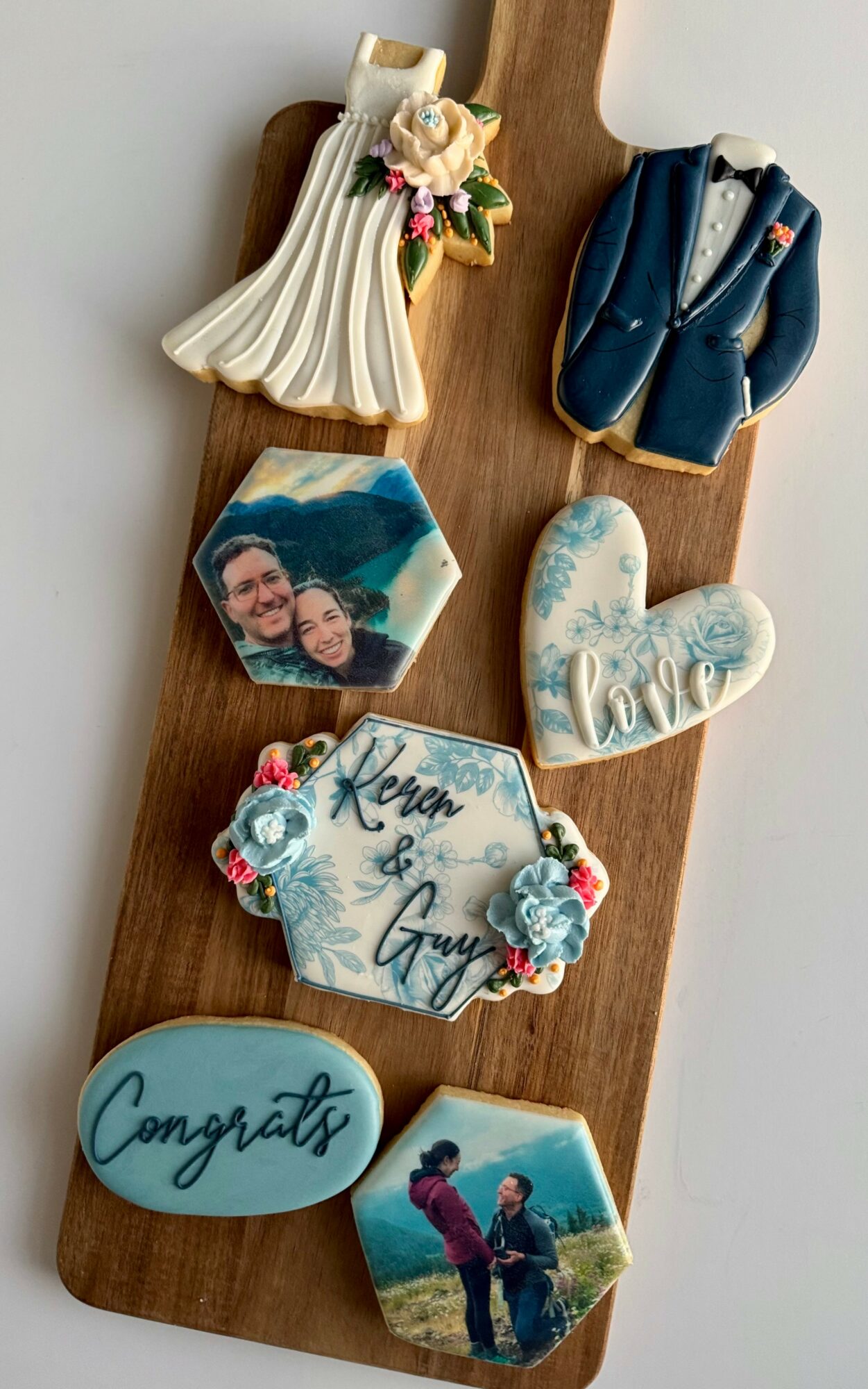 Decorative items including a wedding dress, suit, photo, heart-shaped and oval plaques, and a couple's photo on a wooden board.