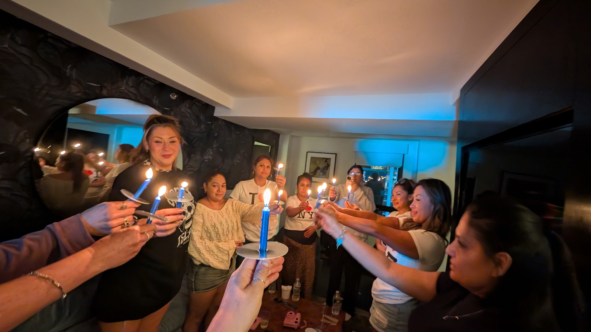 People gather in a room holding lit candles, celebrating together with smiles and a festive atmosphere.