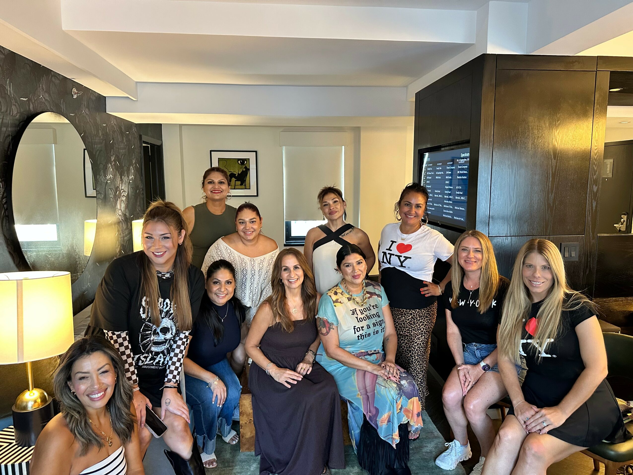 Group of ten women gathered in a living room, some sitting and some standing, smiling at the camera.
