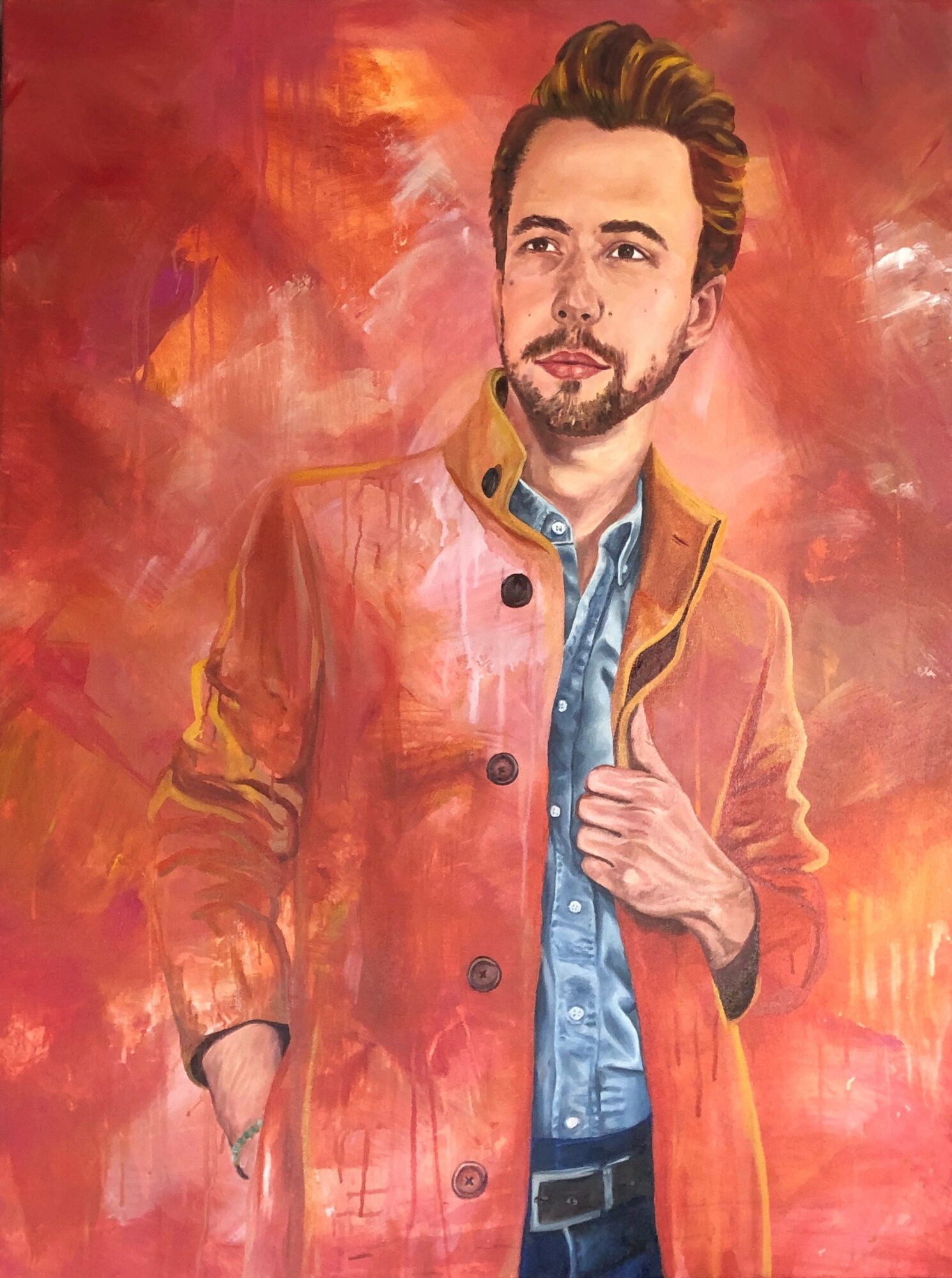 Portrait of a man with styled hair and beard, wearing a brown jacket over a blue shirt, against a red background.