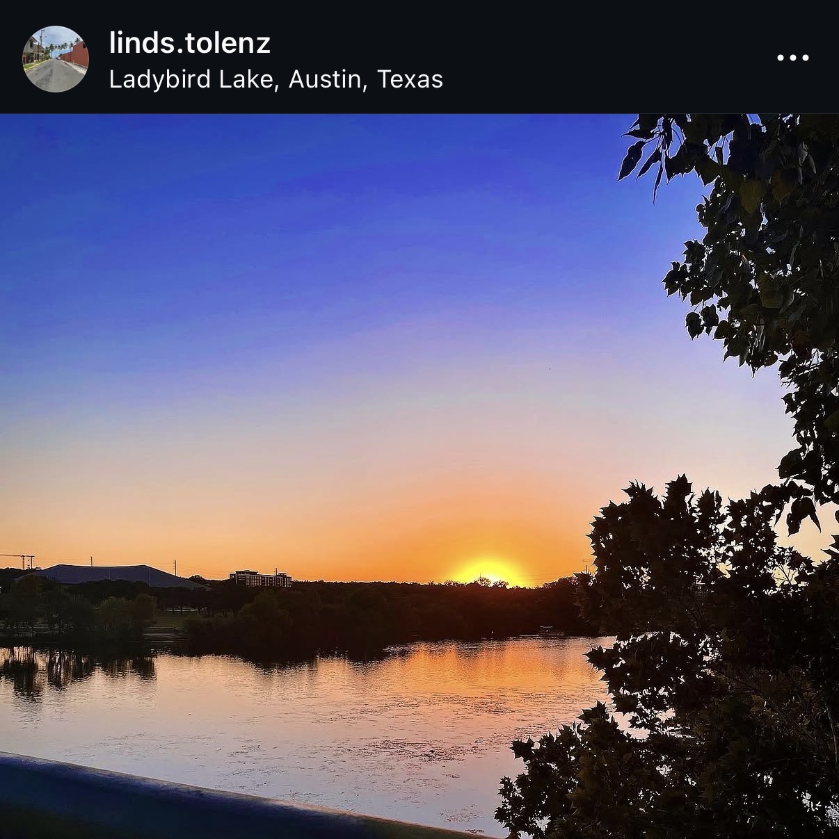Sunset over Ladybird Lake with colorful sky and silhouetted trees, calm water reflecting the sky, in Austin, Texas.