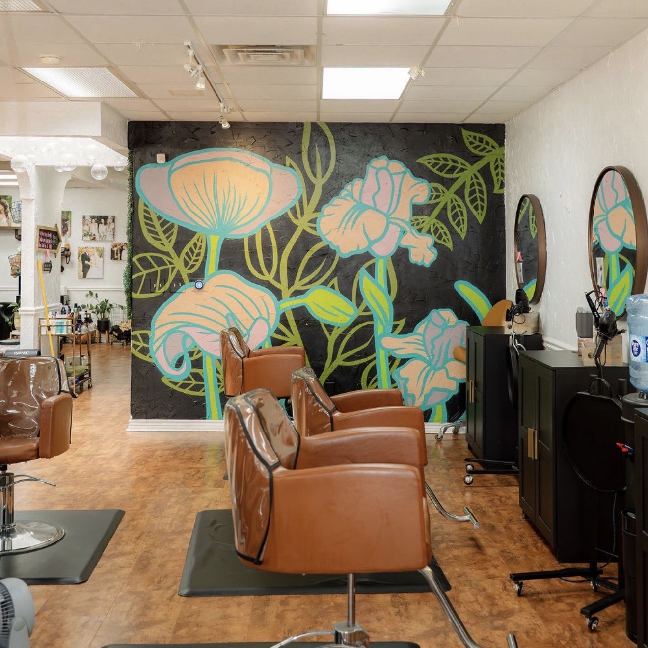 Barber shop interior with brown chairs, a large floral mural on the back wall, and mirrors on the right wall.