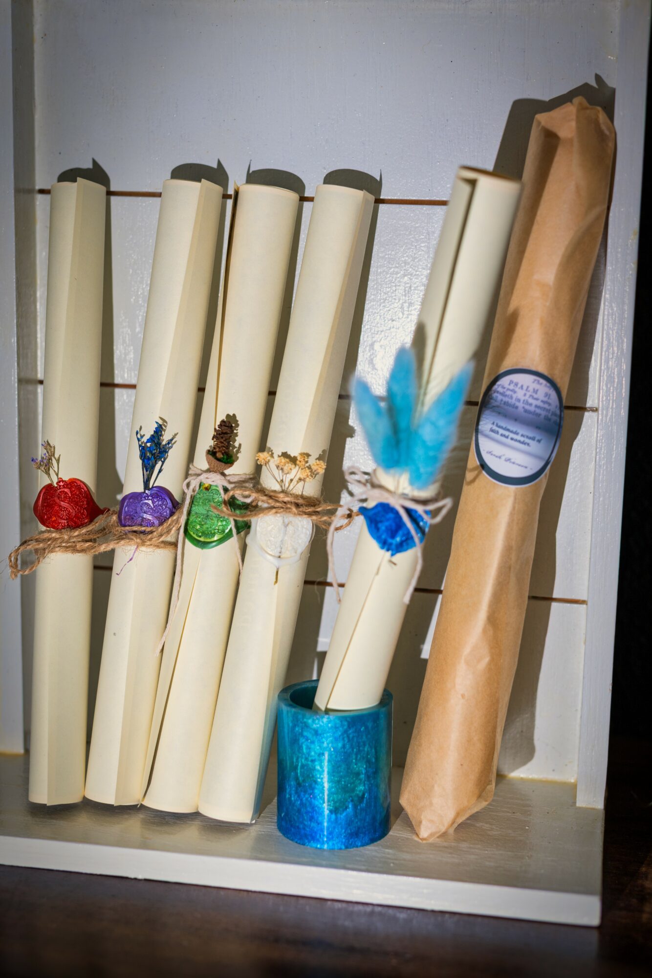 Several rolled-up posters with decorative ribbons and a blue container, leaning against a wall.