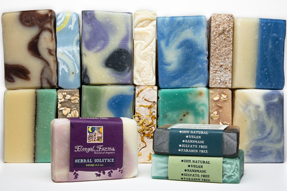 Collection of colorful soap bars with various patterns and textures, some with packaging, arranged in two rows.