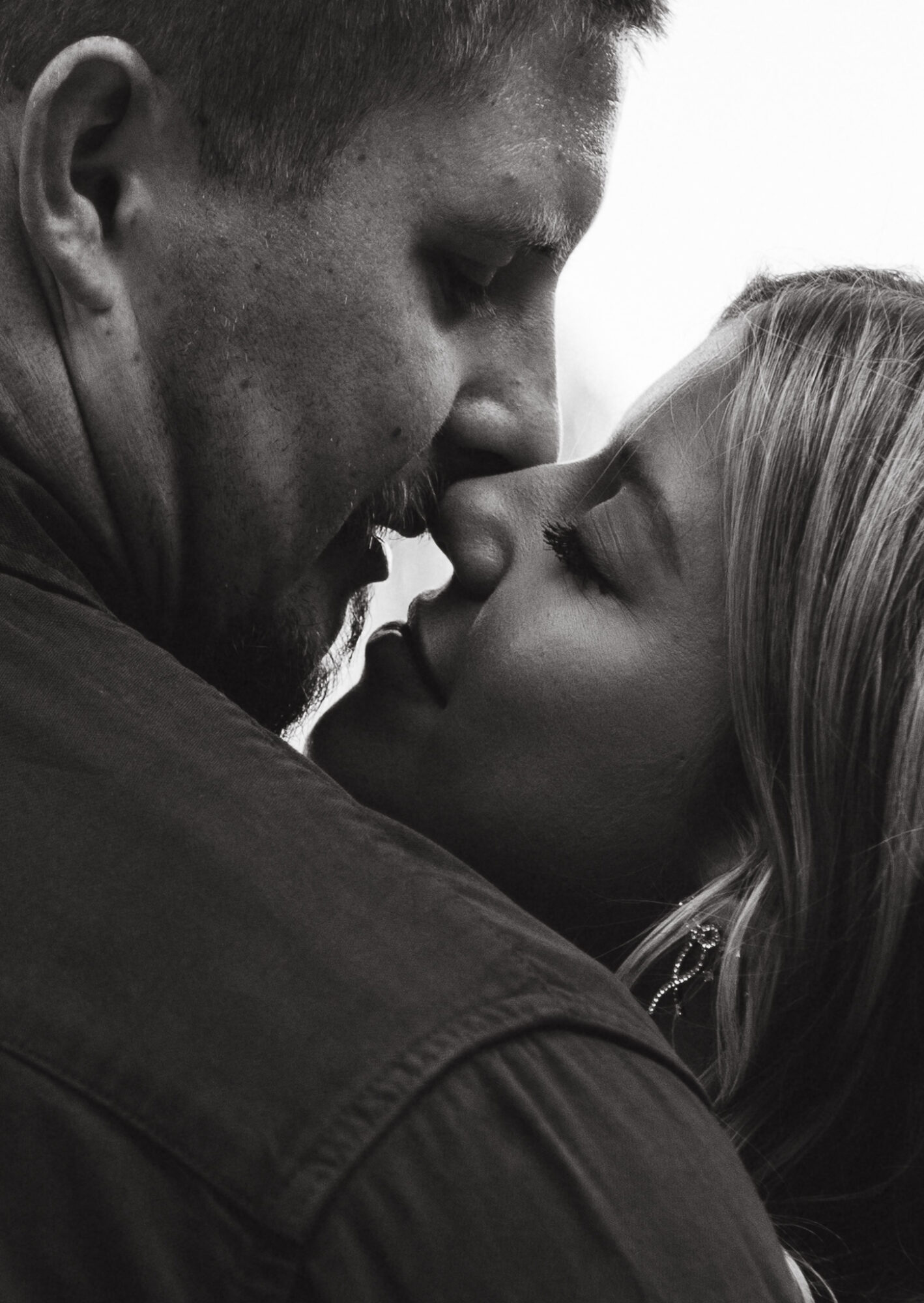 Two people close together, faces nearly touching, in an intimate moment, black and white photograph.