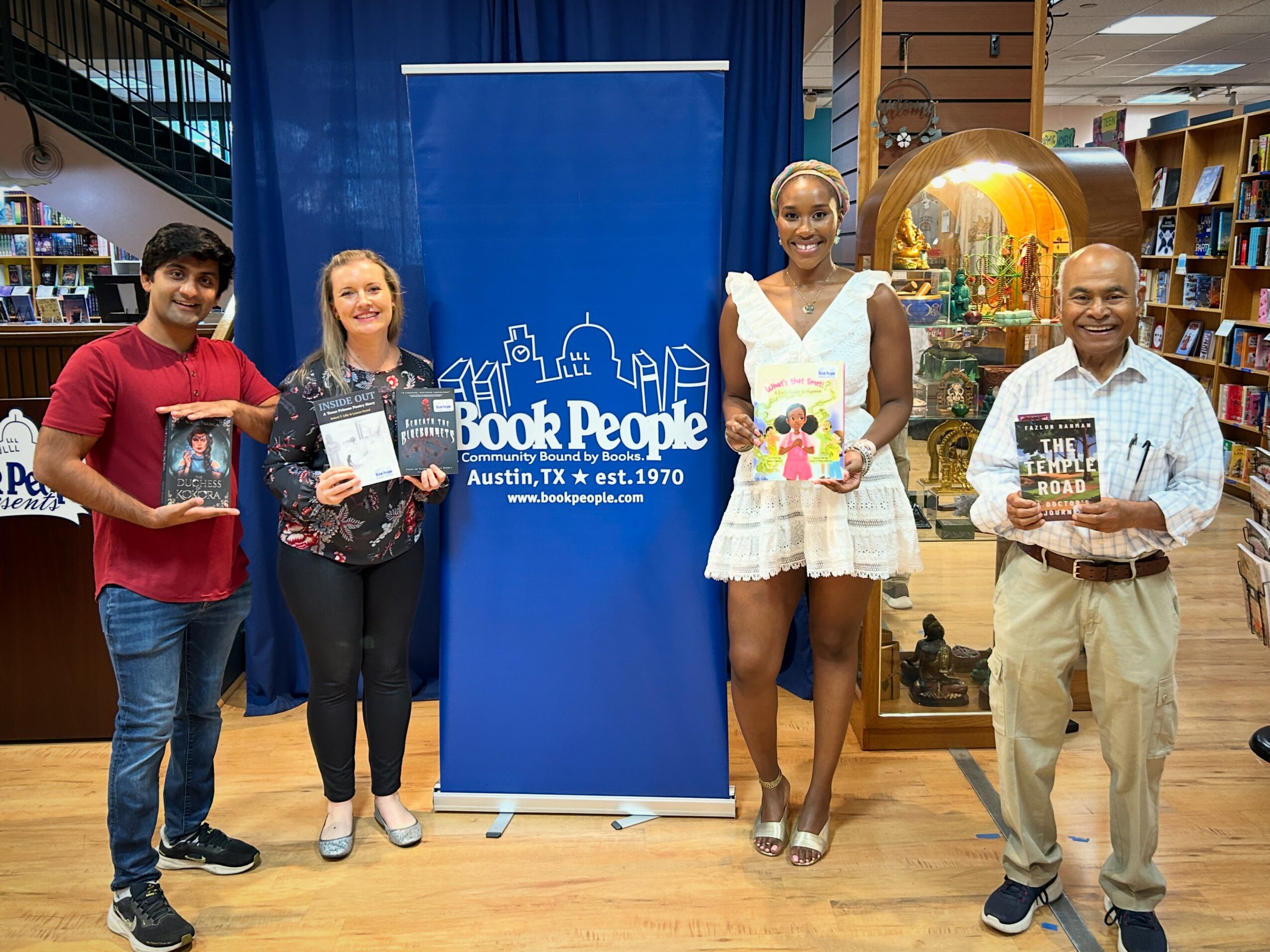 Five people standing in a bookstore, holding books, with a blue Book People banner behind them.