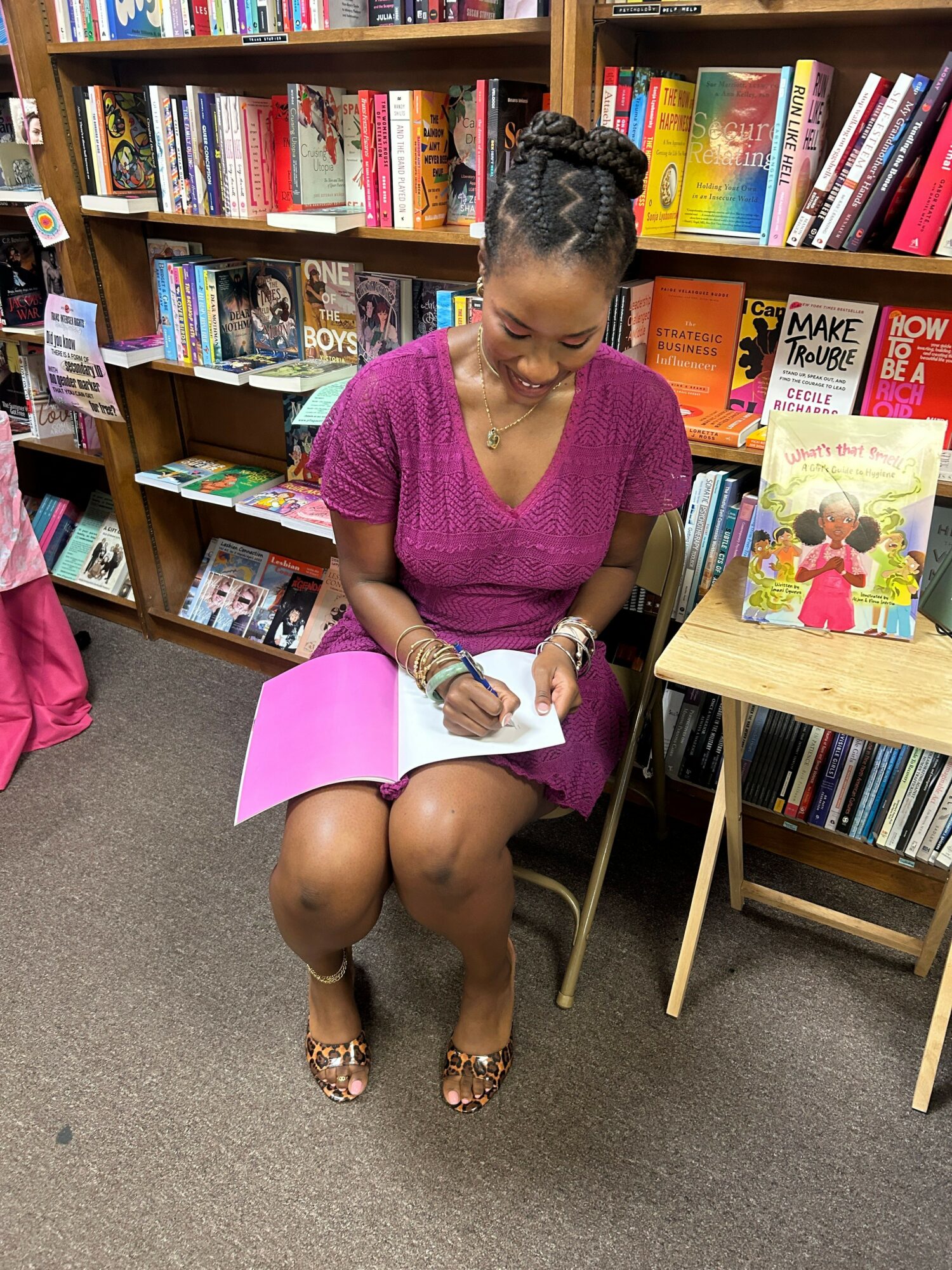 Woman sitting on the floor reading a book in a bookstore, surrounded by shelves of books.