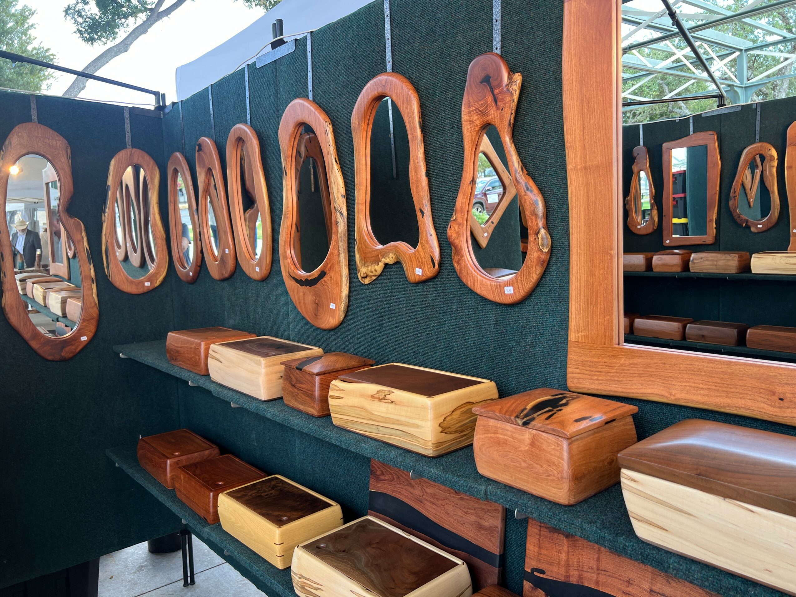 Wooden mirrors and boxes displayed on a shelf with a mirror reflecting part of the room, in a cozy setting.