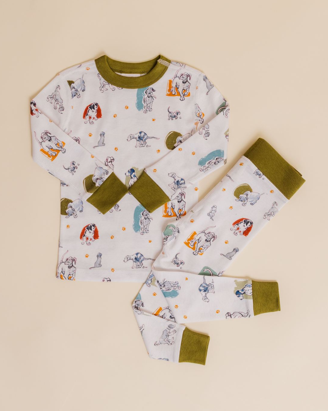 Children's pajamas with space-themed illustrations, green collar and cuffs, laid flat on a beige background.