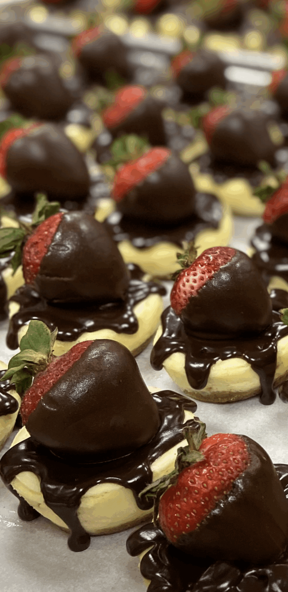 Close-up of chocolate-covered strawberries on a tray with white chocolate and green garnish, blurred background.