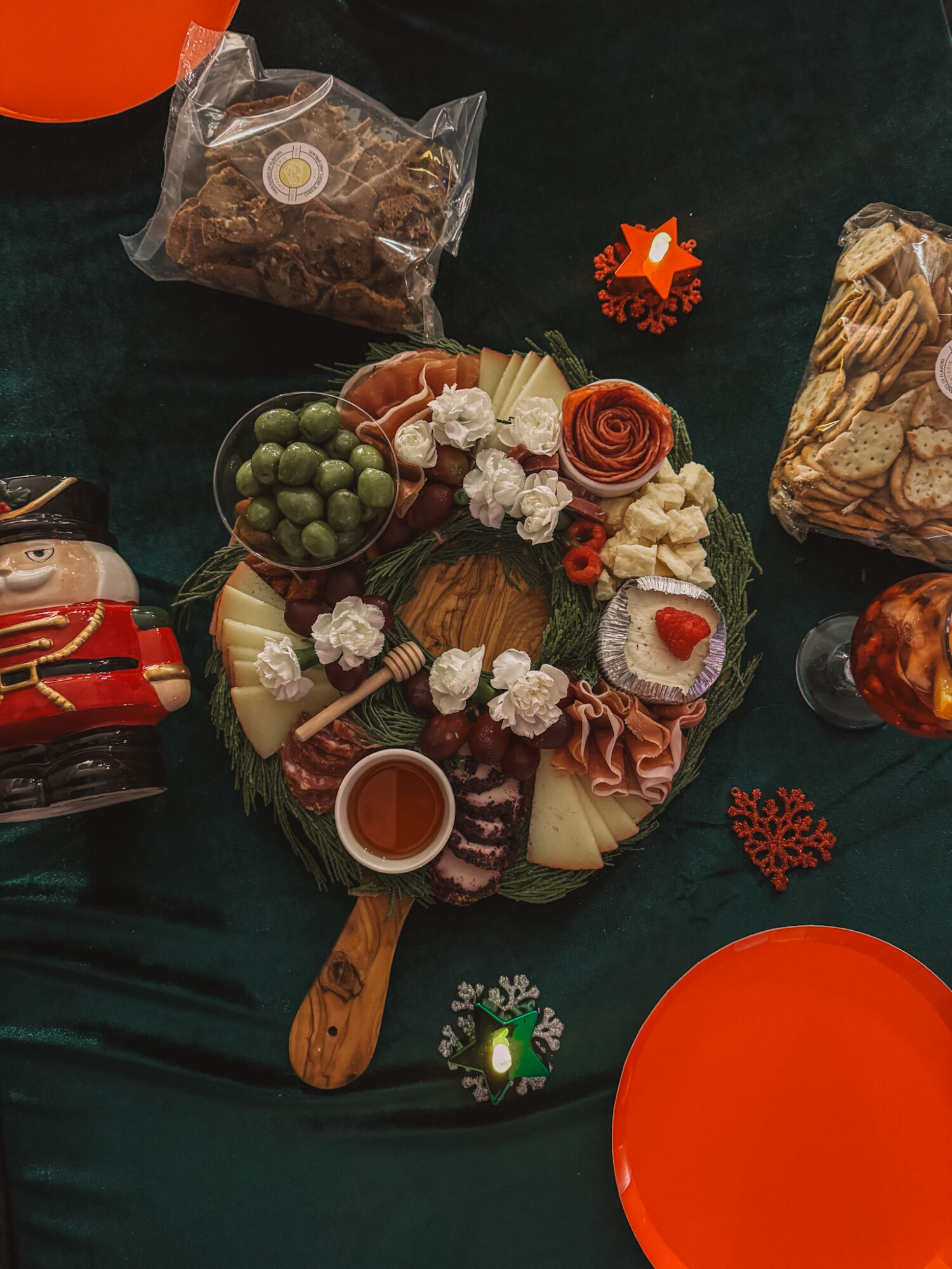 Festive holiday table with cookies, chocolates, and decorations on a dark green cloth, viewed from above.