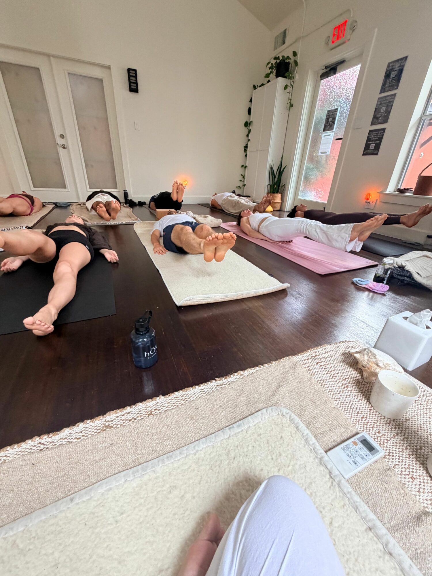 People sitting on a couch in a living room, with a person lying on a mat on the floor, and a door with glass panels in the background.