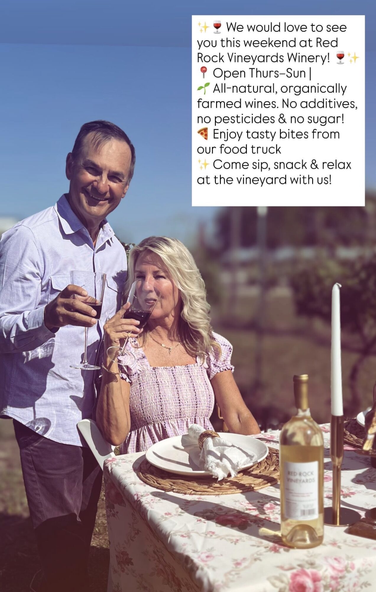 Man and woman enjoying wine outdoors at a table with a bottle, glasses, and a candle, smiling and relaxed.
