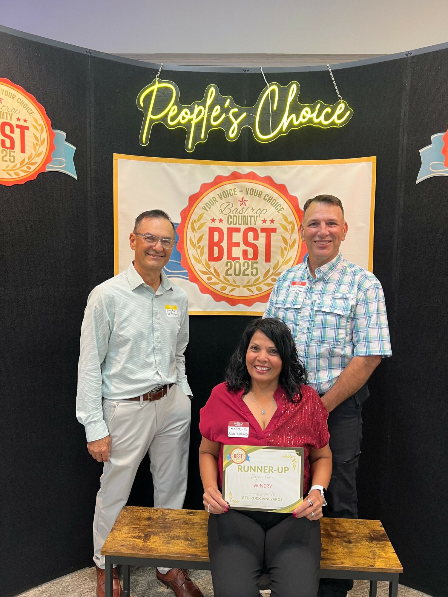Three people standing in front of a black backdrop with a sign that says 'Peachtree Orthopedic' and a badge that says 'Best'.