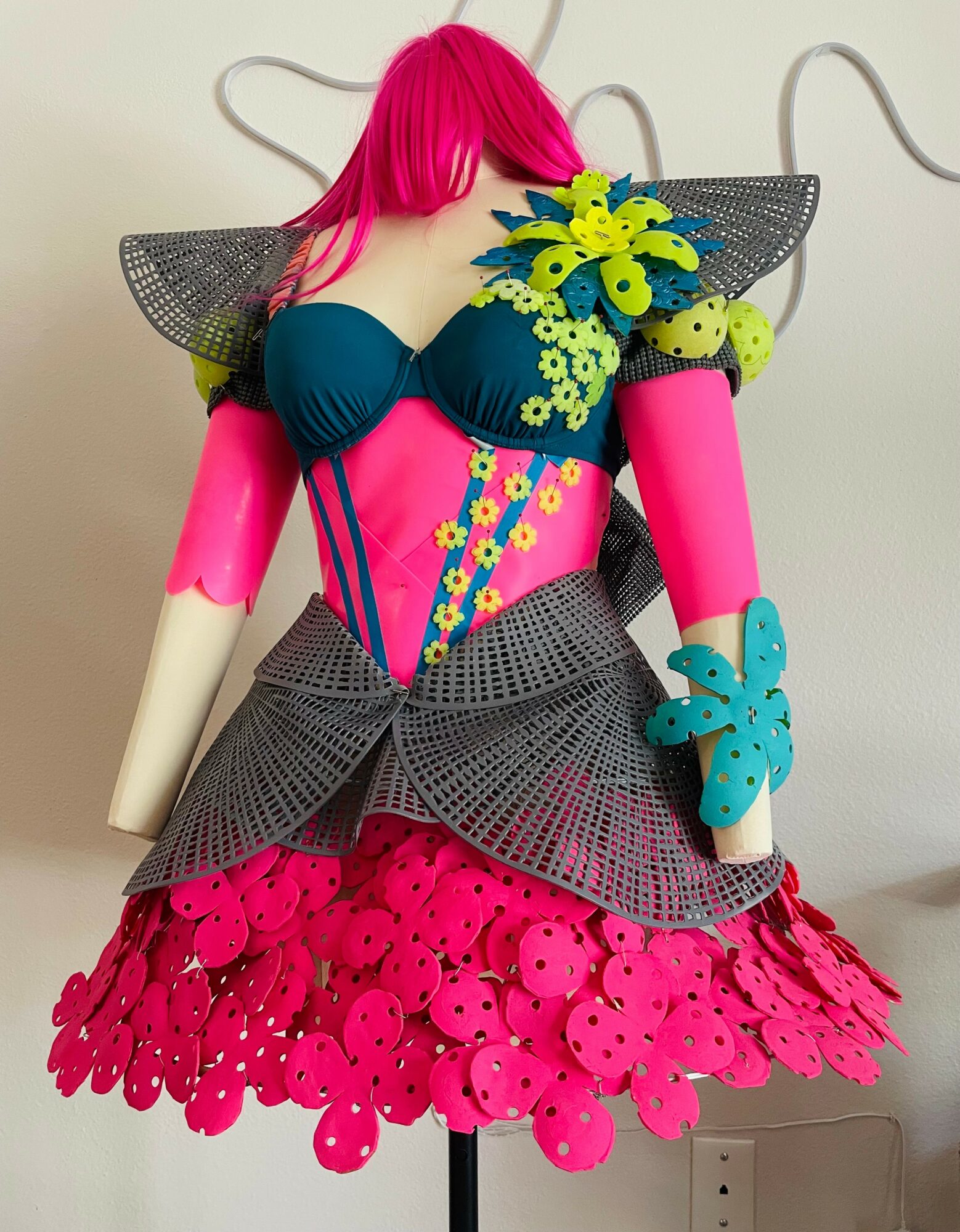 Colorful dress with pink, blue, yellow, and black elements, featuring floral and geometric patterns, displayed on a mannequin.