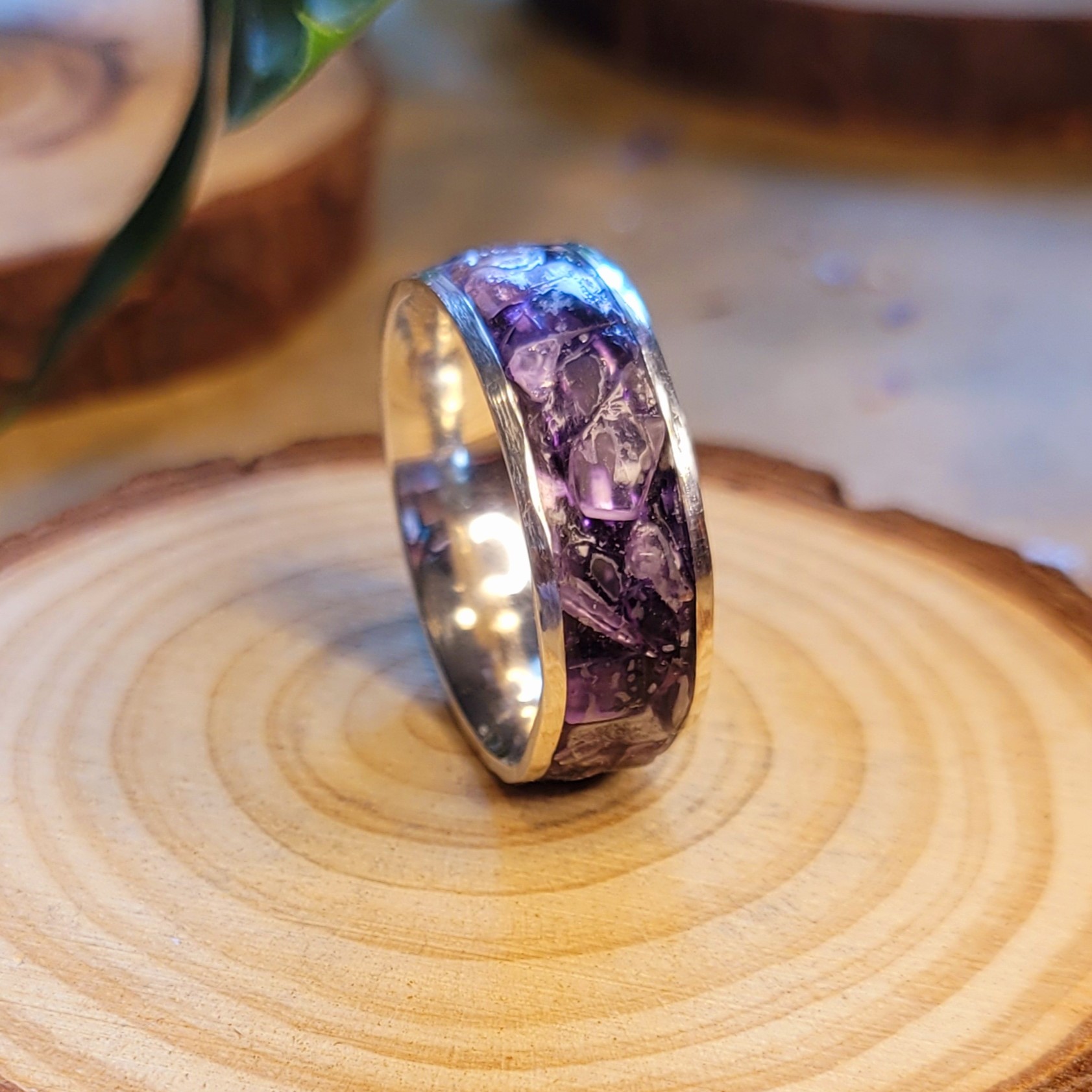 Ring with purple and black pattern on a wooden surface, shiny interior, close-up view.
