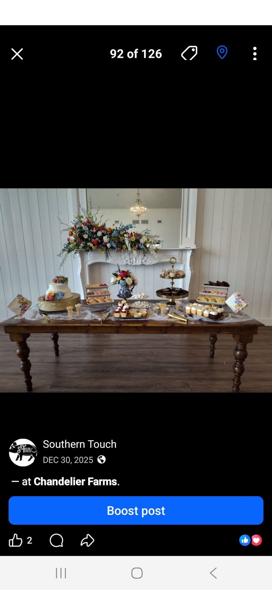 Table with desserts and a floral arrangement in a bright room with white curtains.