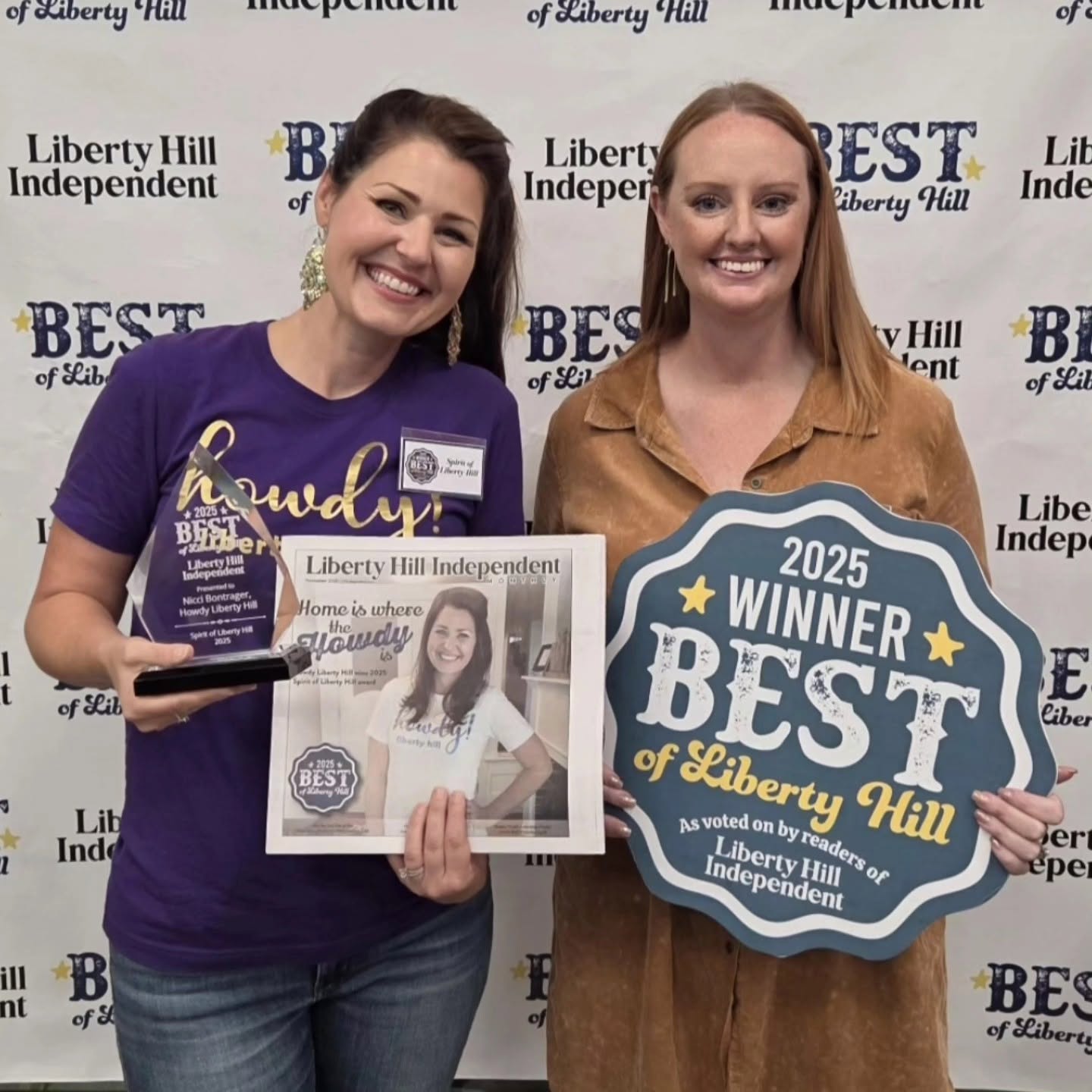 Two women smiling, holding awards and a sign for Liberty Hill Best of 2025, standing in front of a backdrop.