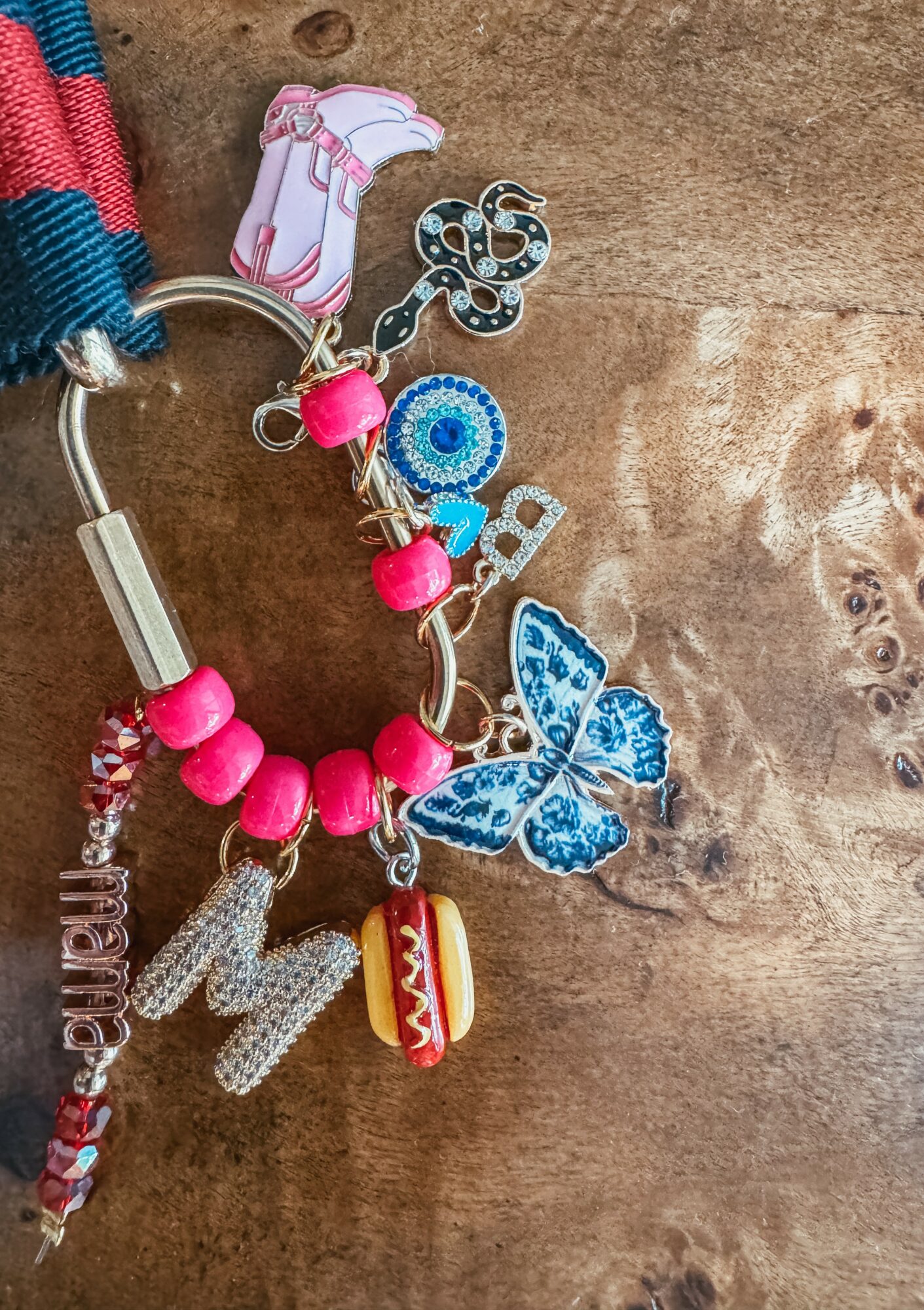 Colorful keychain with charms including a butterfly, hot dog, and beads on a wooden surface.