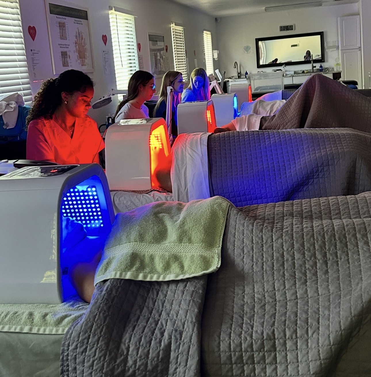 People lying in beds with red and blue lights, watching a screen in a room with posters on the wall.