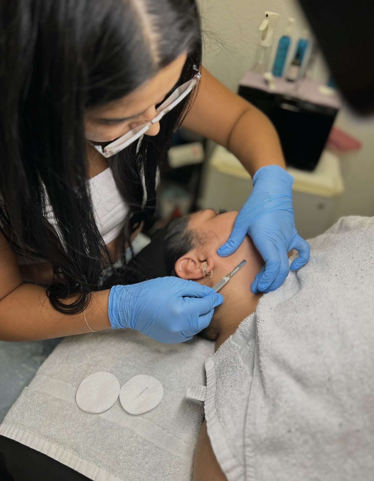Medical professional in blue gloves administers injection to a person's neck, with medical supplies in background.