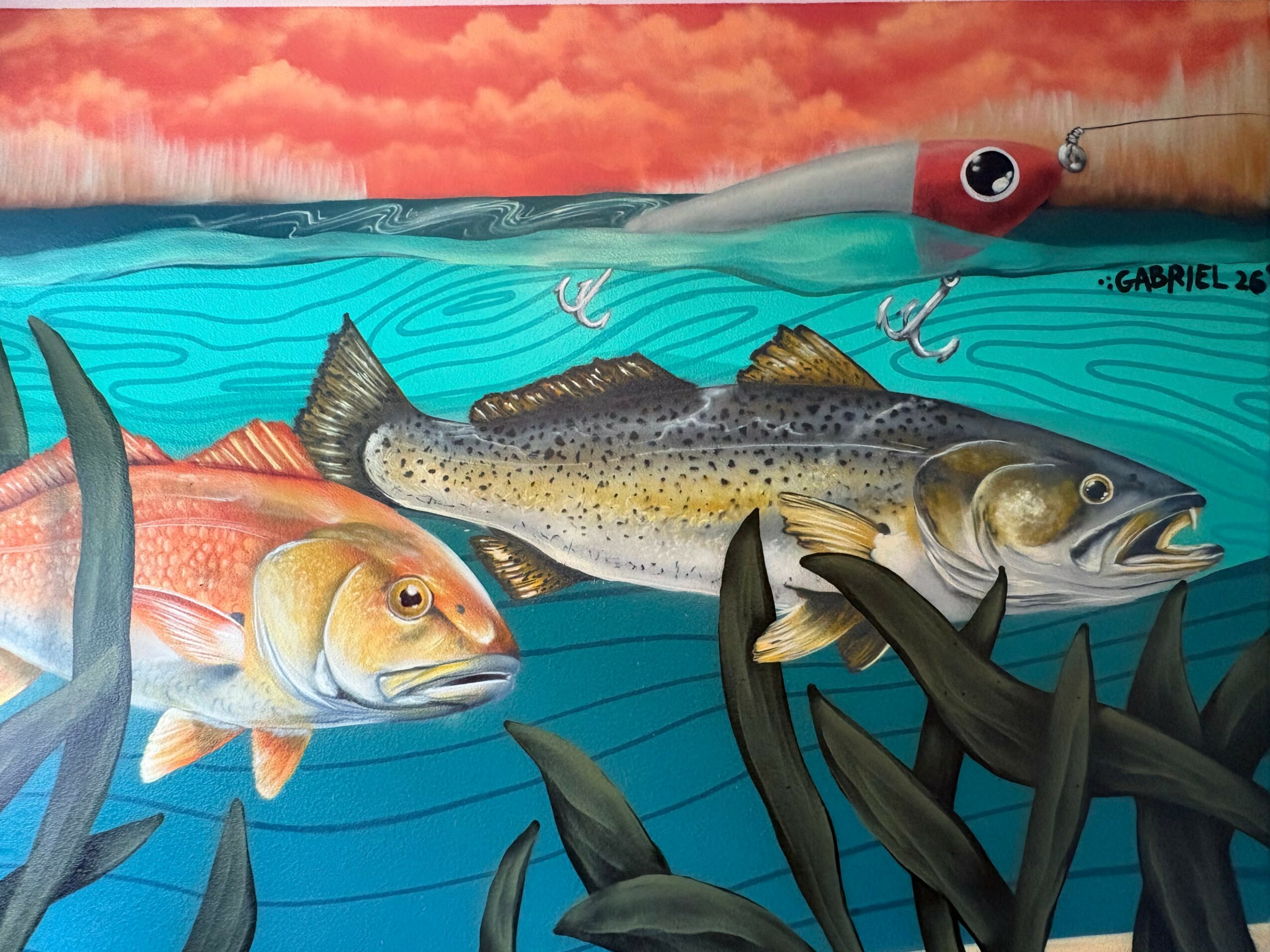 Underwater scene with fish, a fishing lure, and aquatic plants, with a cloudy sky above the water surface.