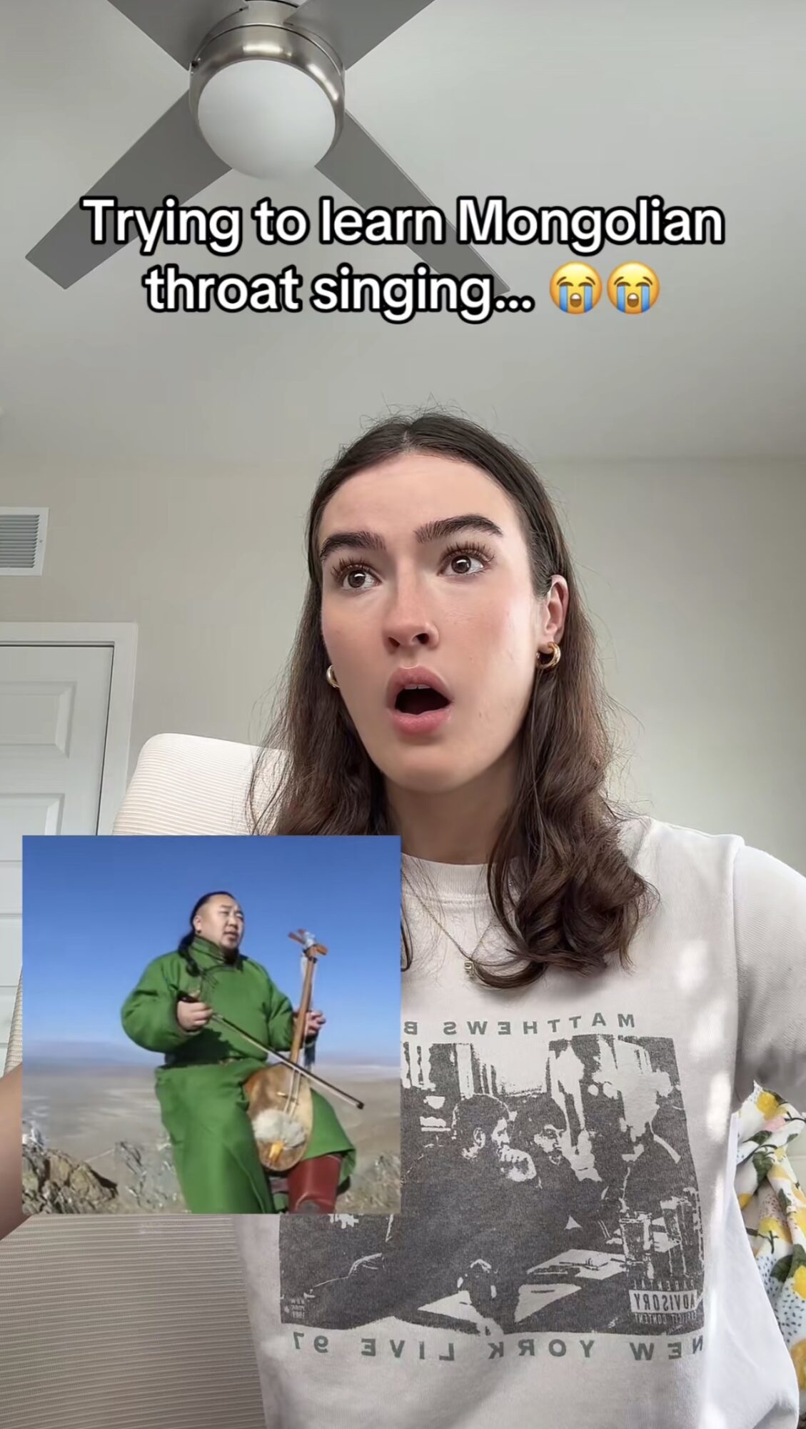 Woman with surprised expression, ceiling fan above, text about learning Mongolian throat singing, person in green jacket holding a guitar in outdoor setting
