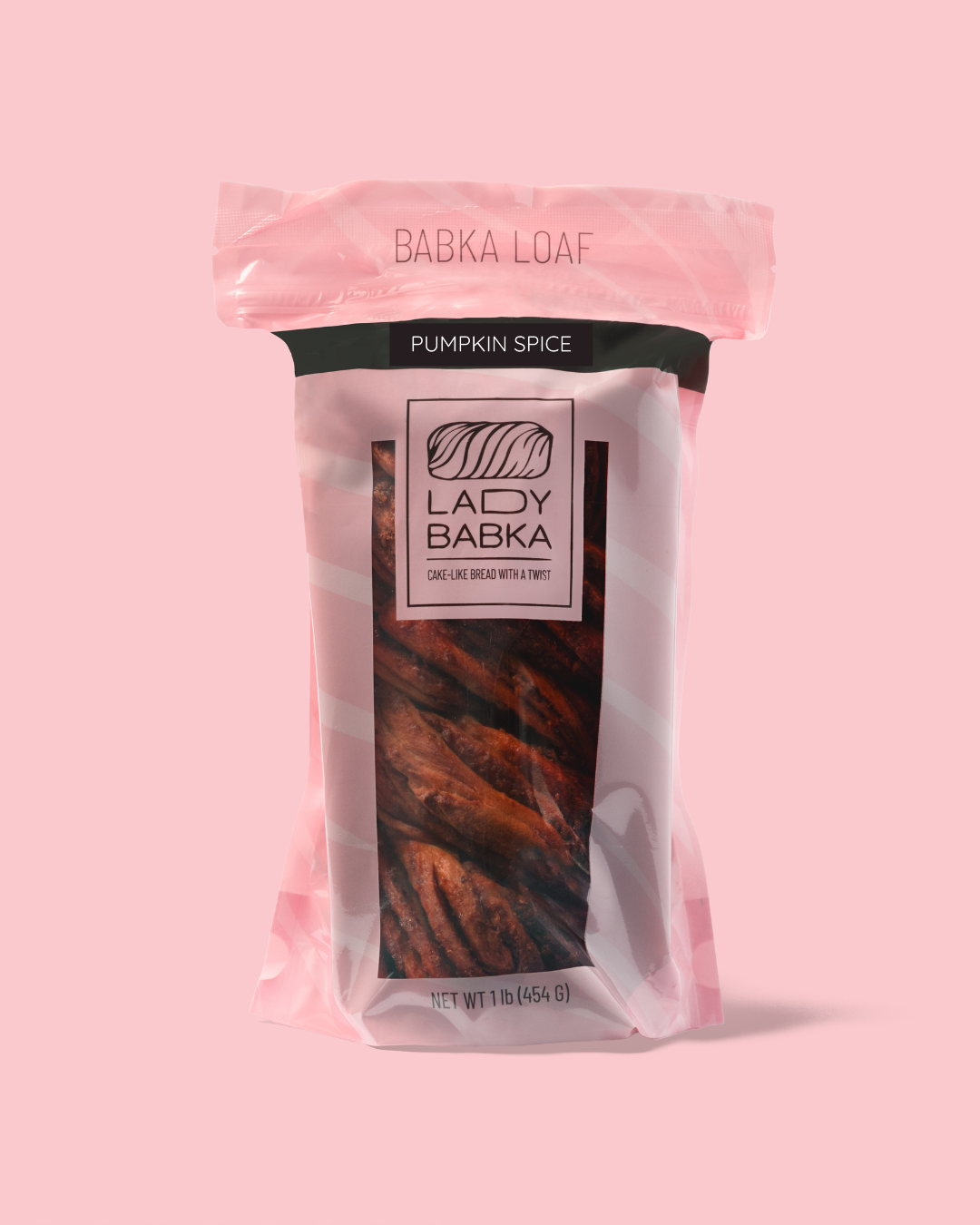 Pumpkin spice babka loaf in clear packaging with pink and black labels, against a pink background.