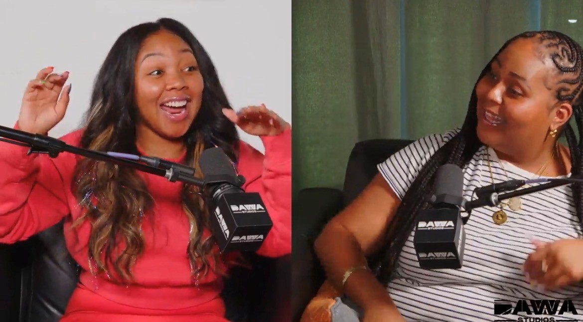 Two women speaking into microphones during a podcast, smiling and engaging with each other, one in a red top, the other in a striped shirt.