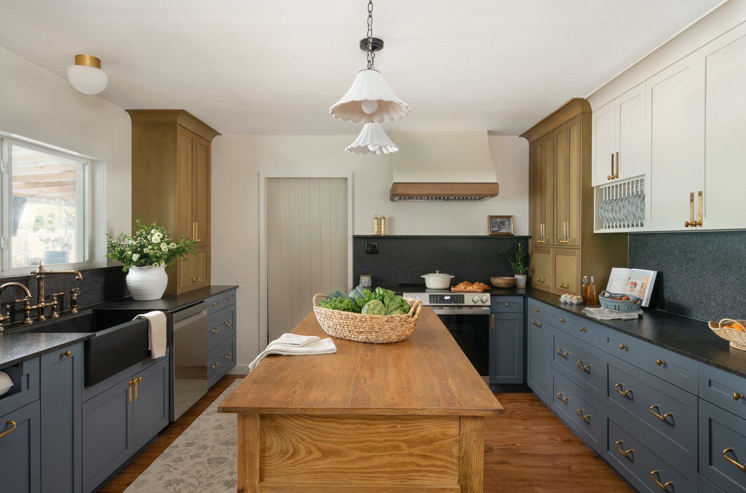 Kitchen with wooden and blue cabinets, a wooden island, and hanging light fixtures, with a window and various kitchen items.