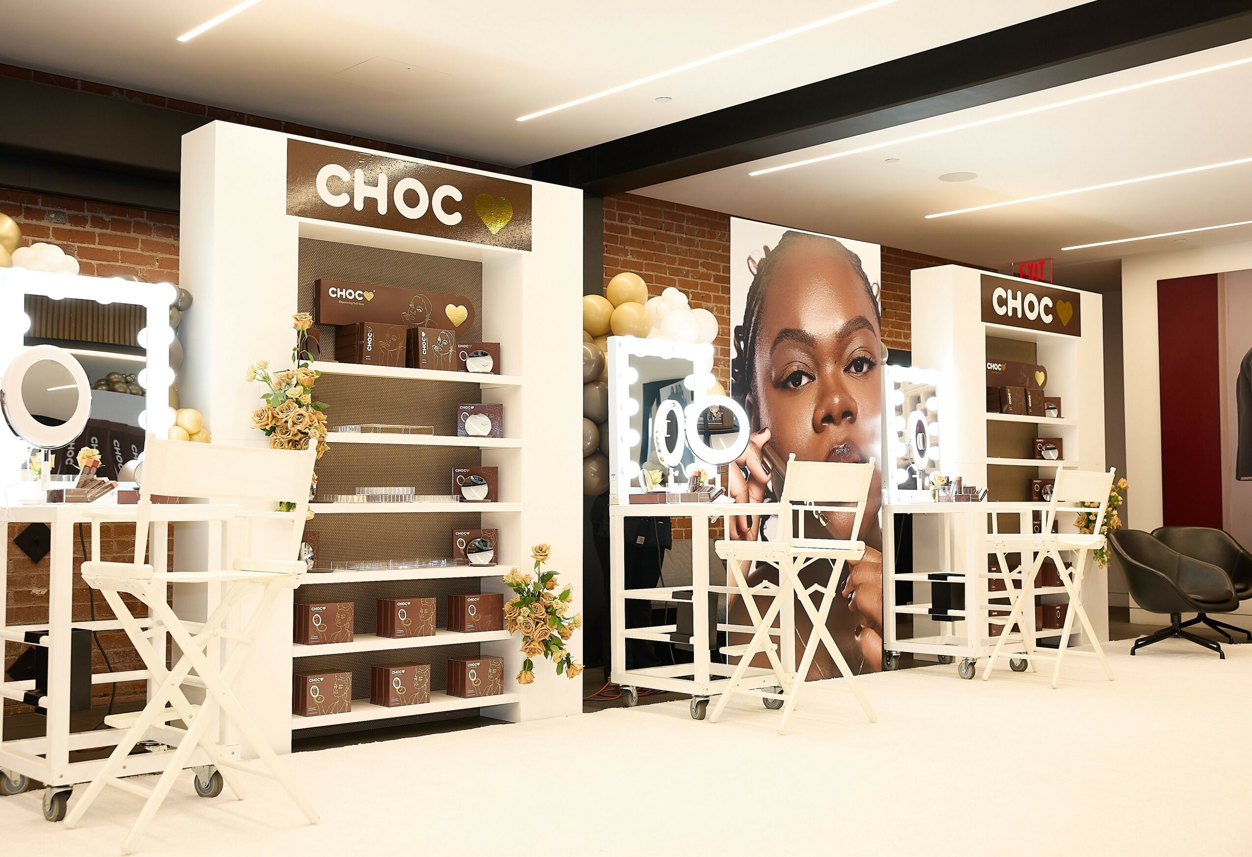 Display shelves with chocolates, a large poster of a woman's face, and seating area in a store interior.
