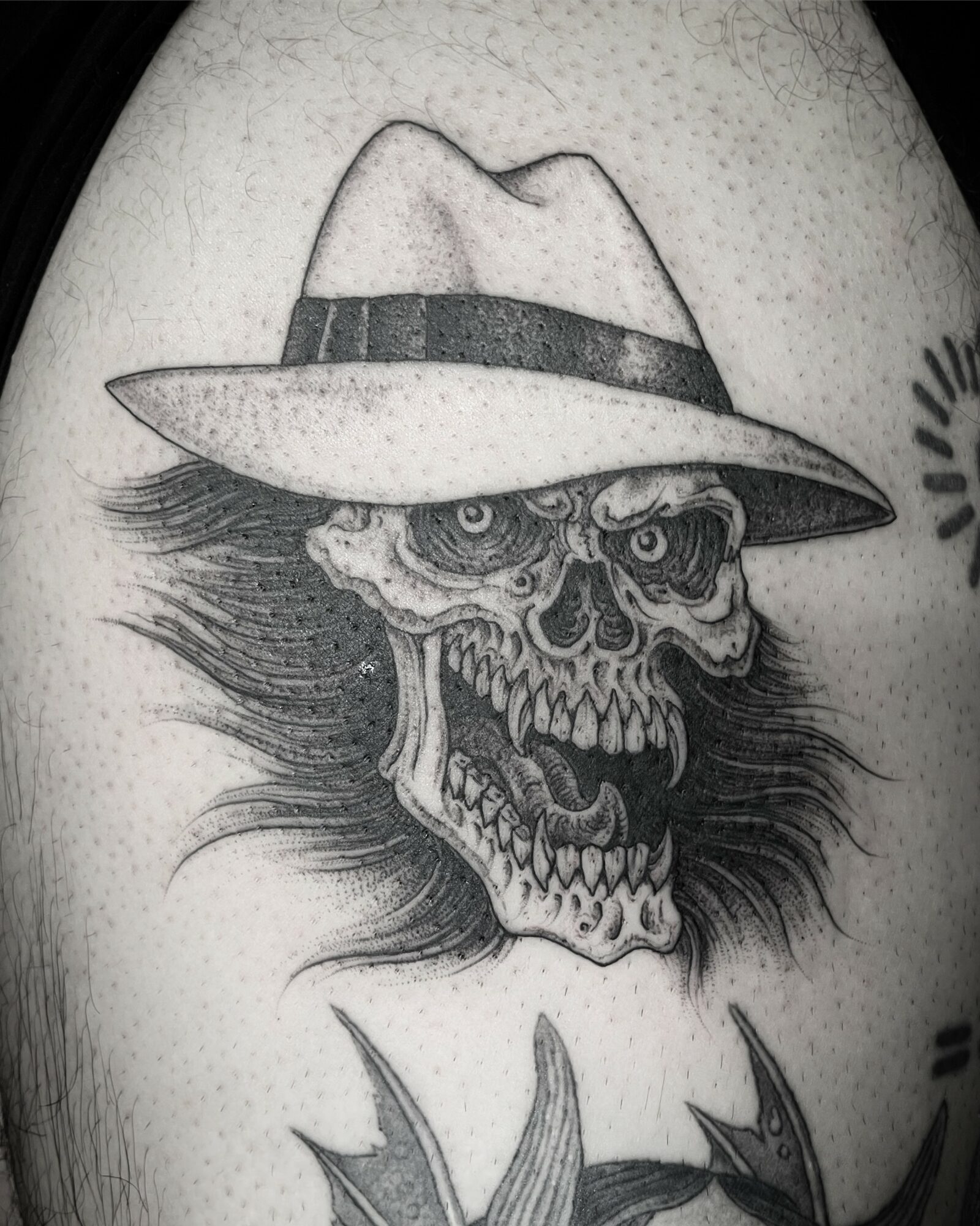 Skull with a hat and long hair, detailed black and gray tattoo, on skin with small dots, realistic style.