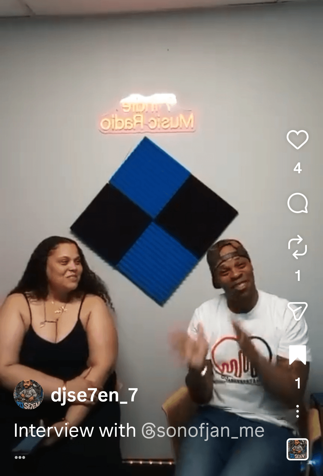 Two people sitting in front of a wall with a blue and black diamond-shaped decoration, smiling and talking.