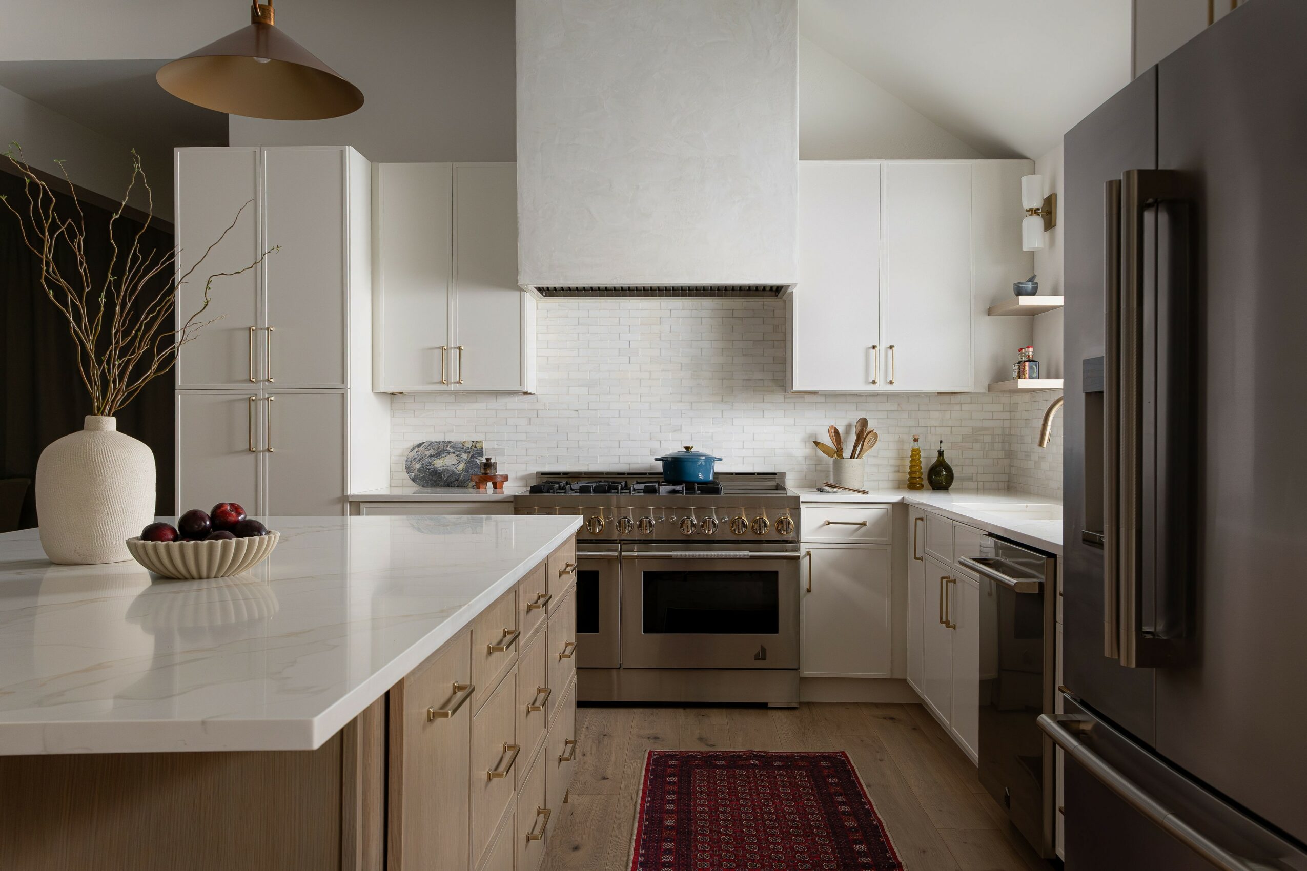 Modern kitchen with white cabinets, stainless steel appliances, and a red rug on the floor.