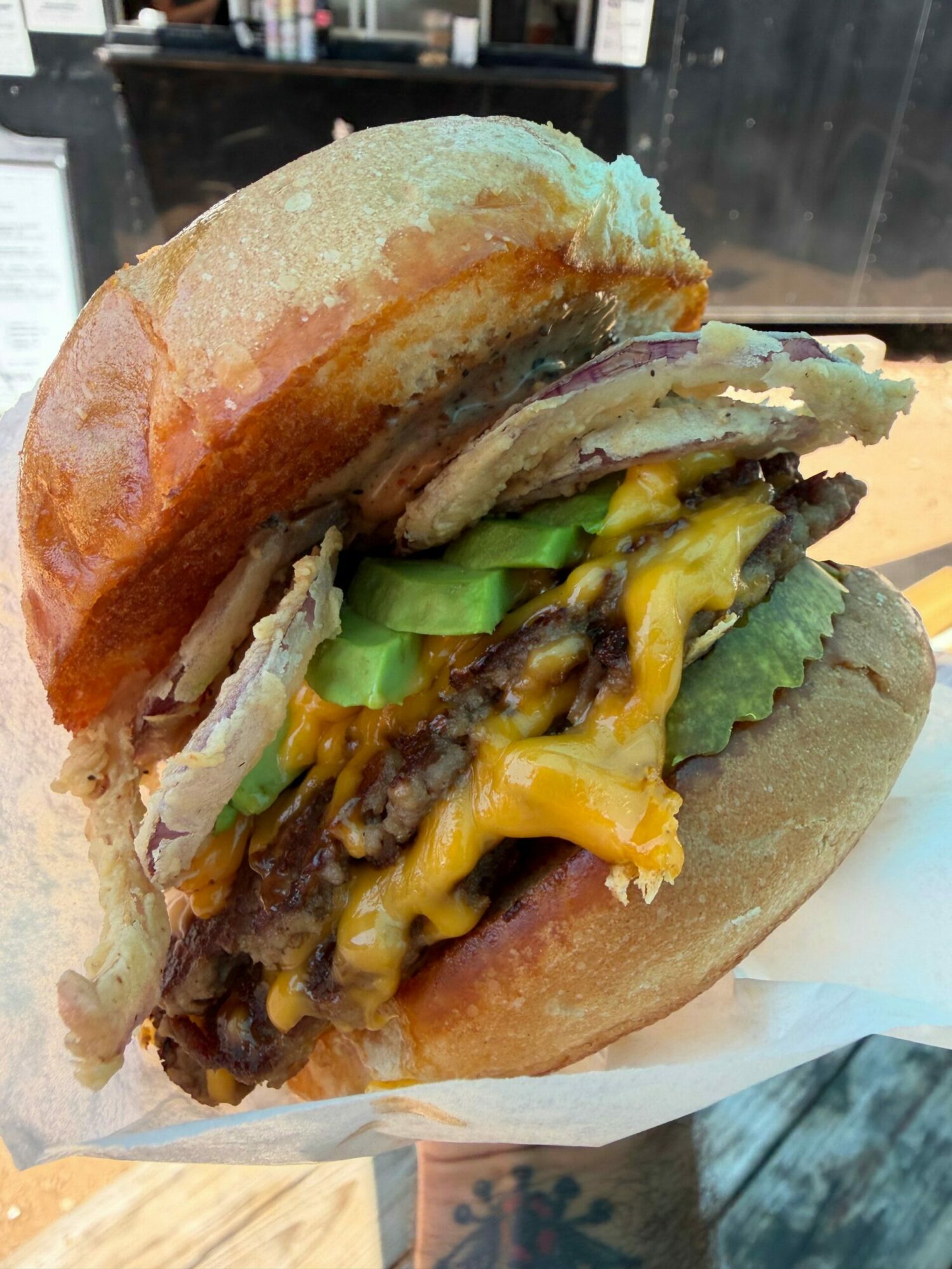 Close-up of a burger with lettuce, cheese, beef patty, and bun, viewed from the side.
