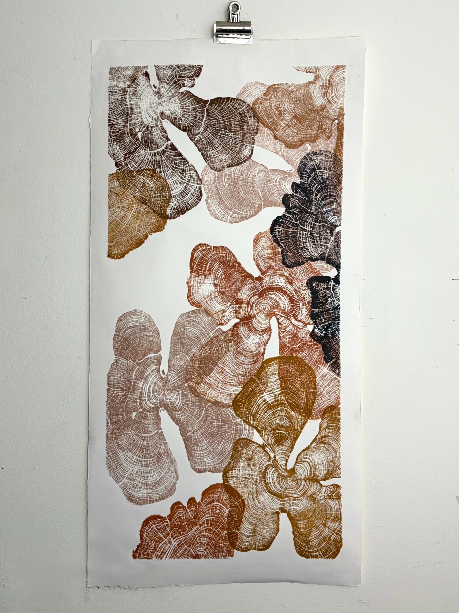 A printed artwork with multiple abstract, textured shapes in shades of brown, black, and gray on a white background.