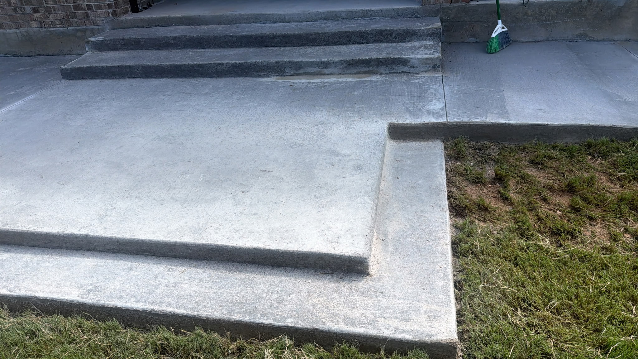Concrete steps leading to a higher level, with a ramp and grassy area nearby.